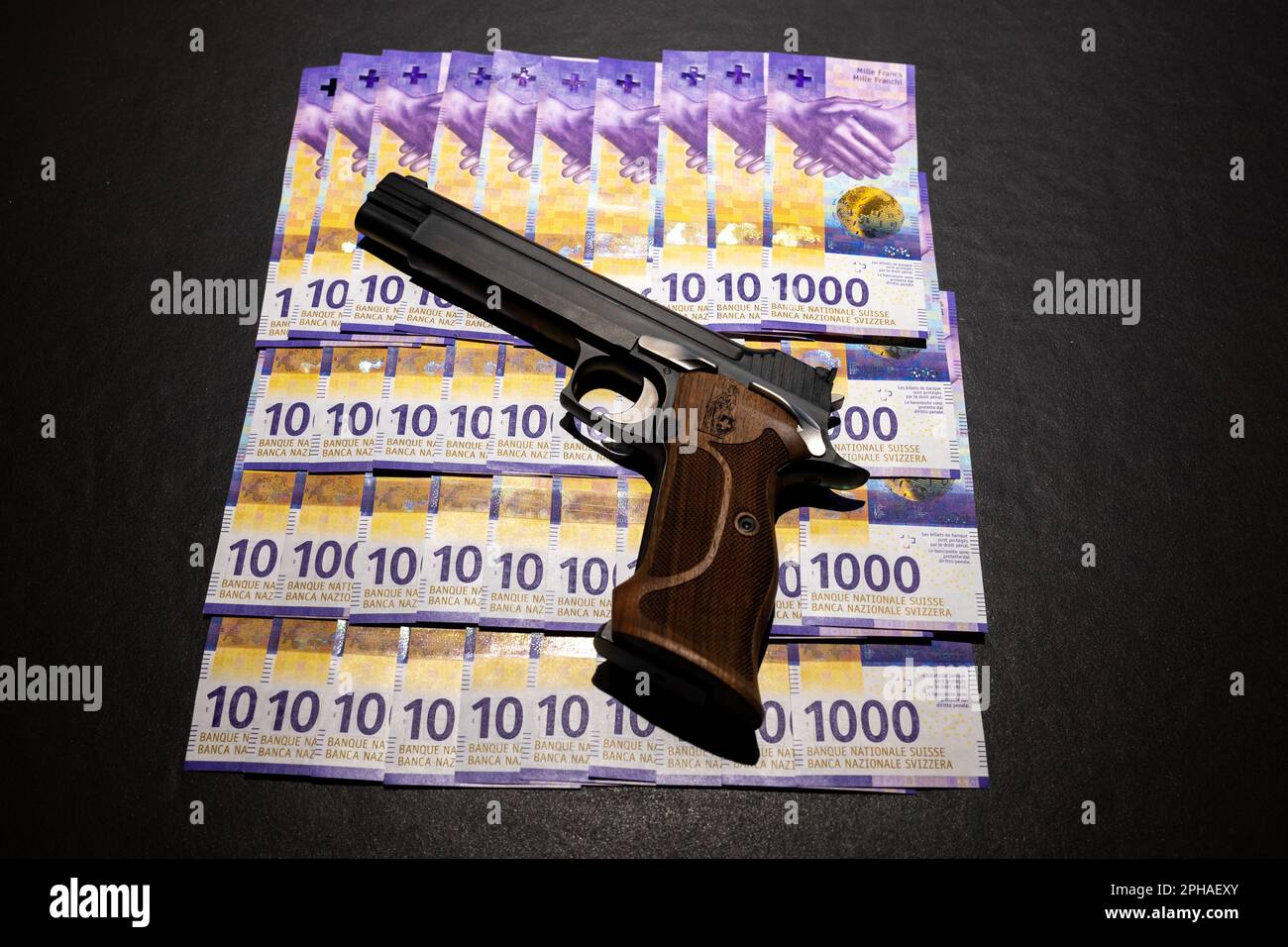 Elegante pistola semiautomatica 9mm con Swiss Helvetia Symbol appoggiata sulla banconota da 1000 franchi svizzeri. Foto Stock