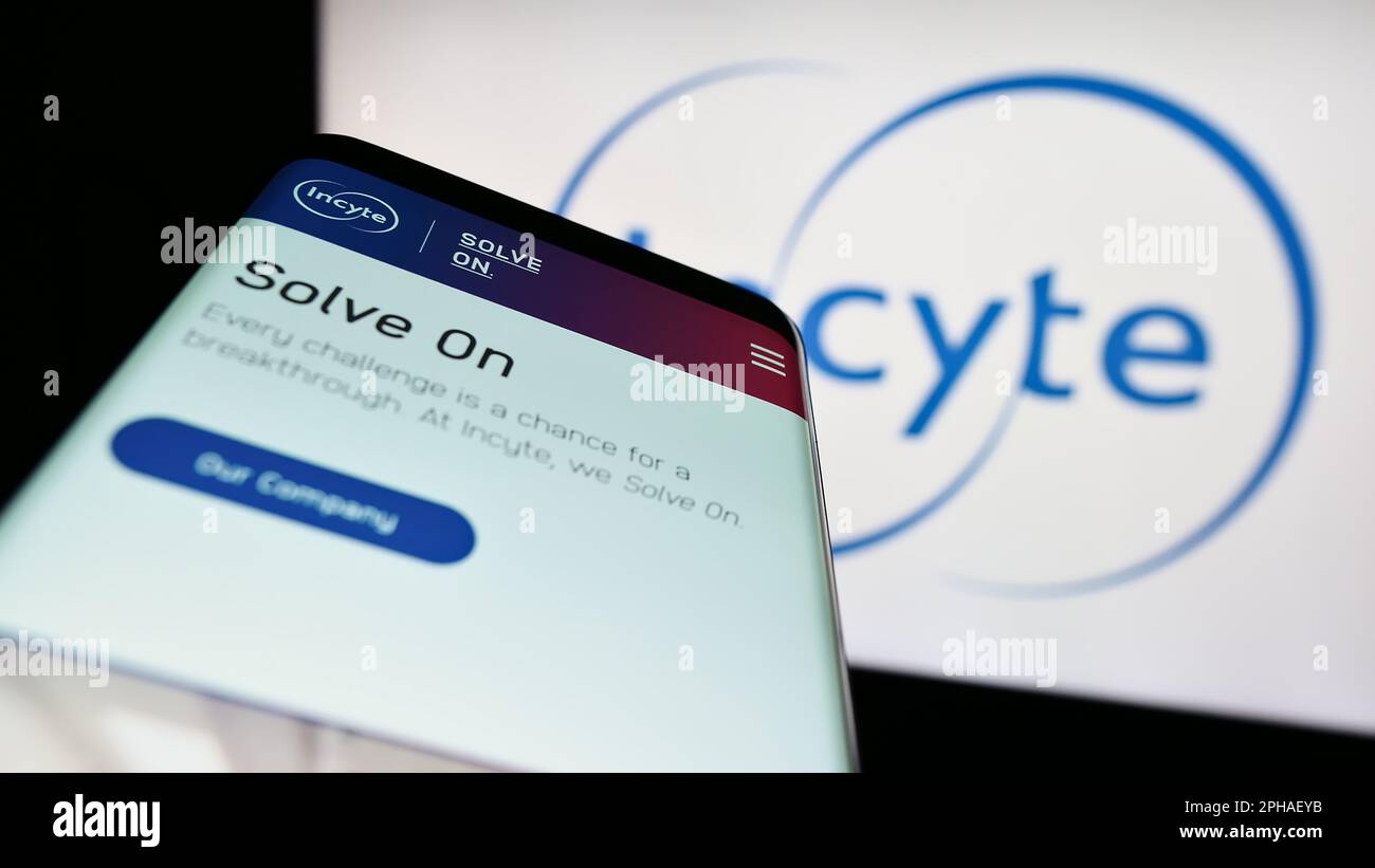 Telefono cellulare con sito web della società farmaceutica americana Incyte Corporation sullo schermo di fronte al logo. Messa a fuoco in alto a sinistra del display del telefono. Foto Stock