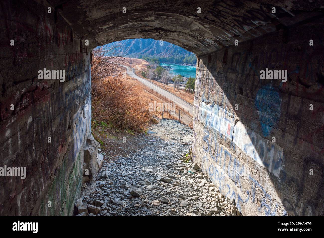 L'uscita dall'edit grotta risplende di luce naturale al buio in Altai sullo sfondo del fiume e delle montagne. Foto Stock