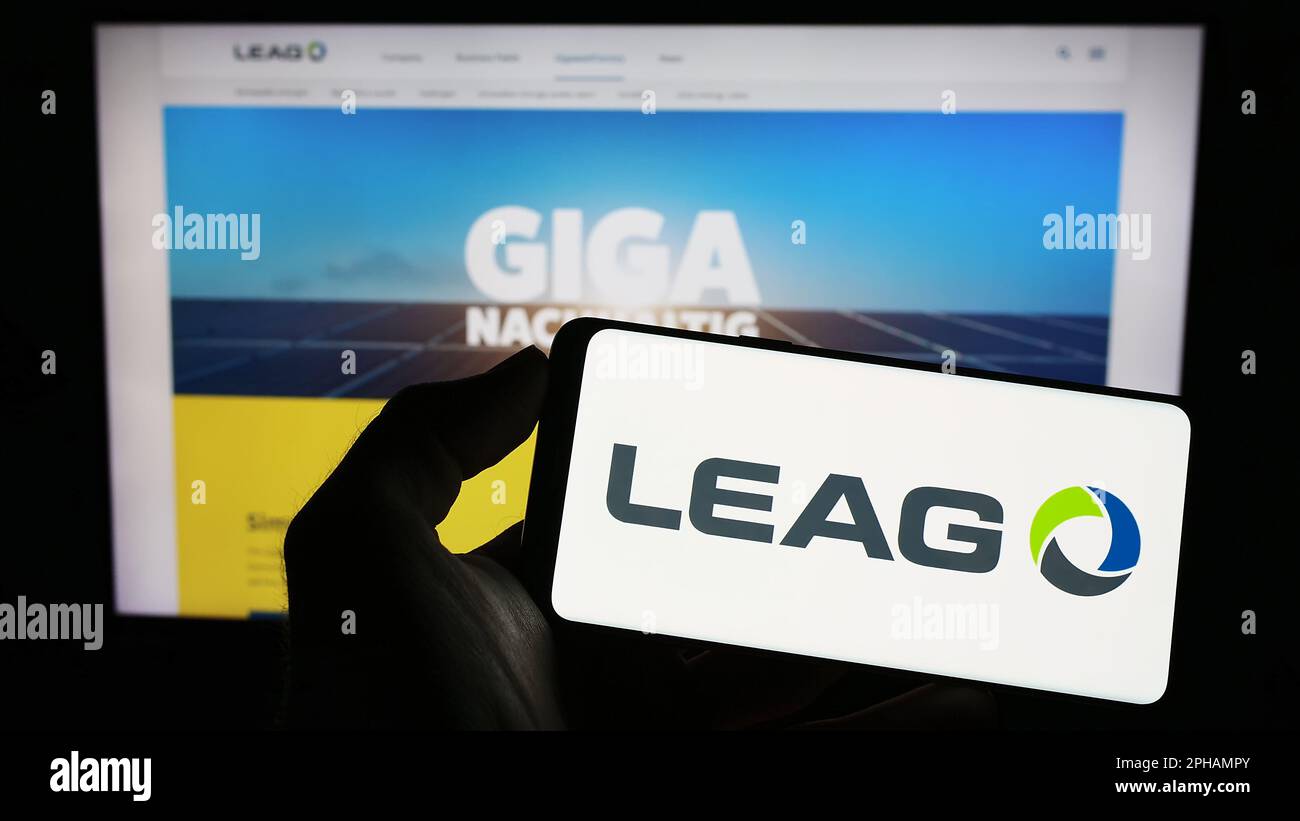 Persona che tiene il cellulare con il logo della società tedesca di energia LEAG sullo schermo di fronte al sito web aziendale. Messa a fuoco sul display del telefono. Foto Stock