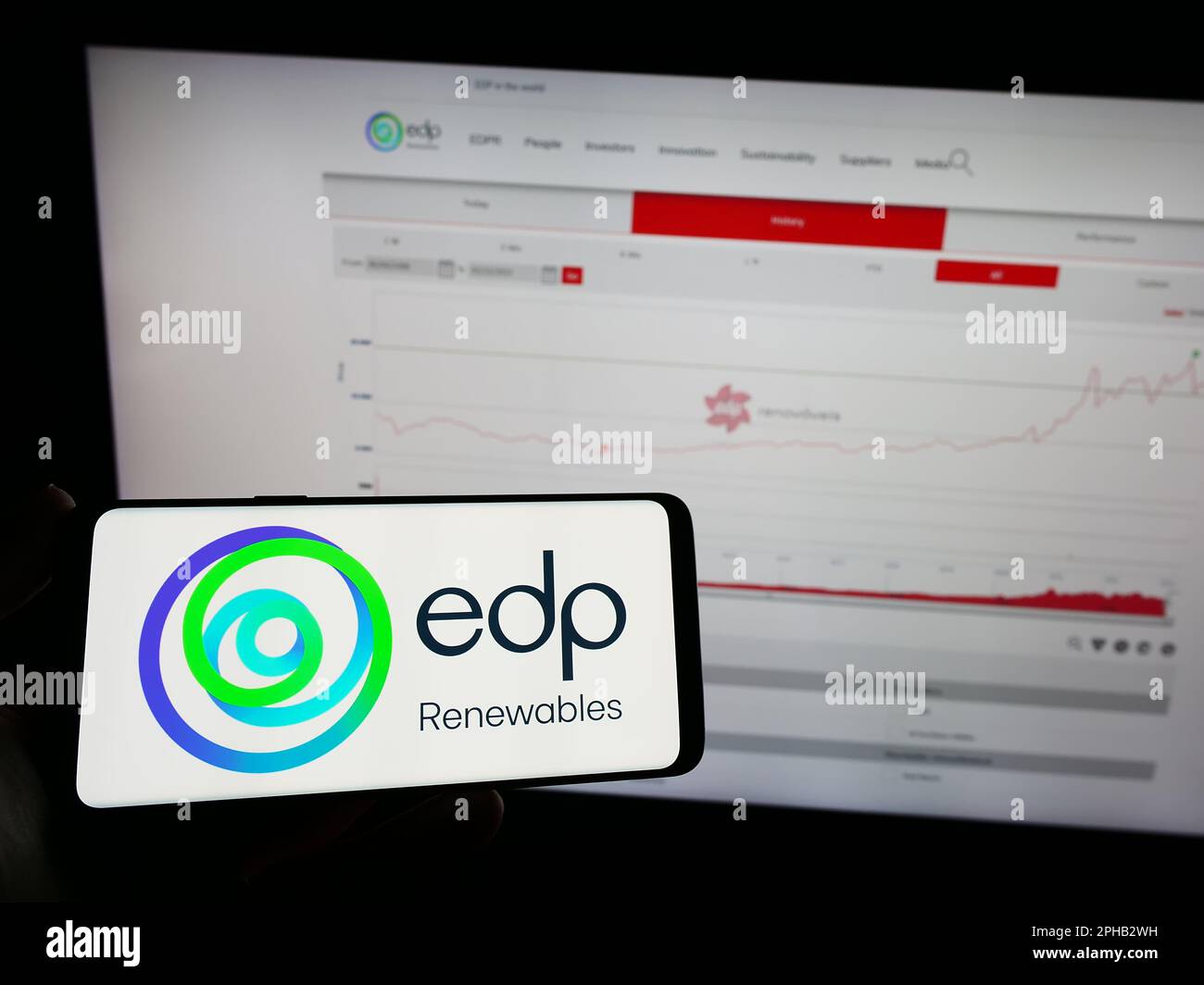 Persona che tiene il telefono cellulare con il logo della società spagnola di energia EDP Renovaveis SA (EDPR) sullo schermo di fronte alla pagina web. Messa a fuoco sul display del telefono. Foto Stock