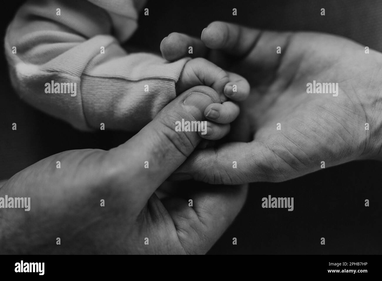 Primo piano dei genitori che tengono la mano del loro neonato. Foto Stock