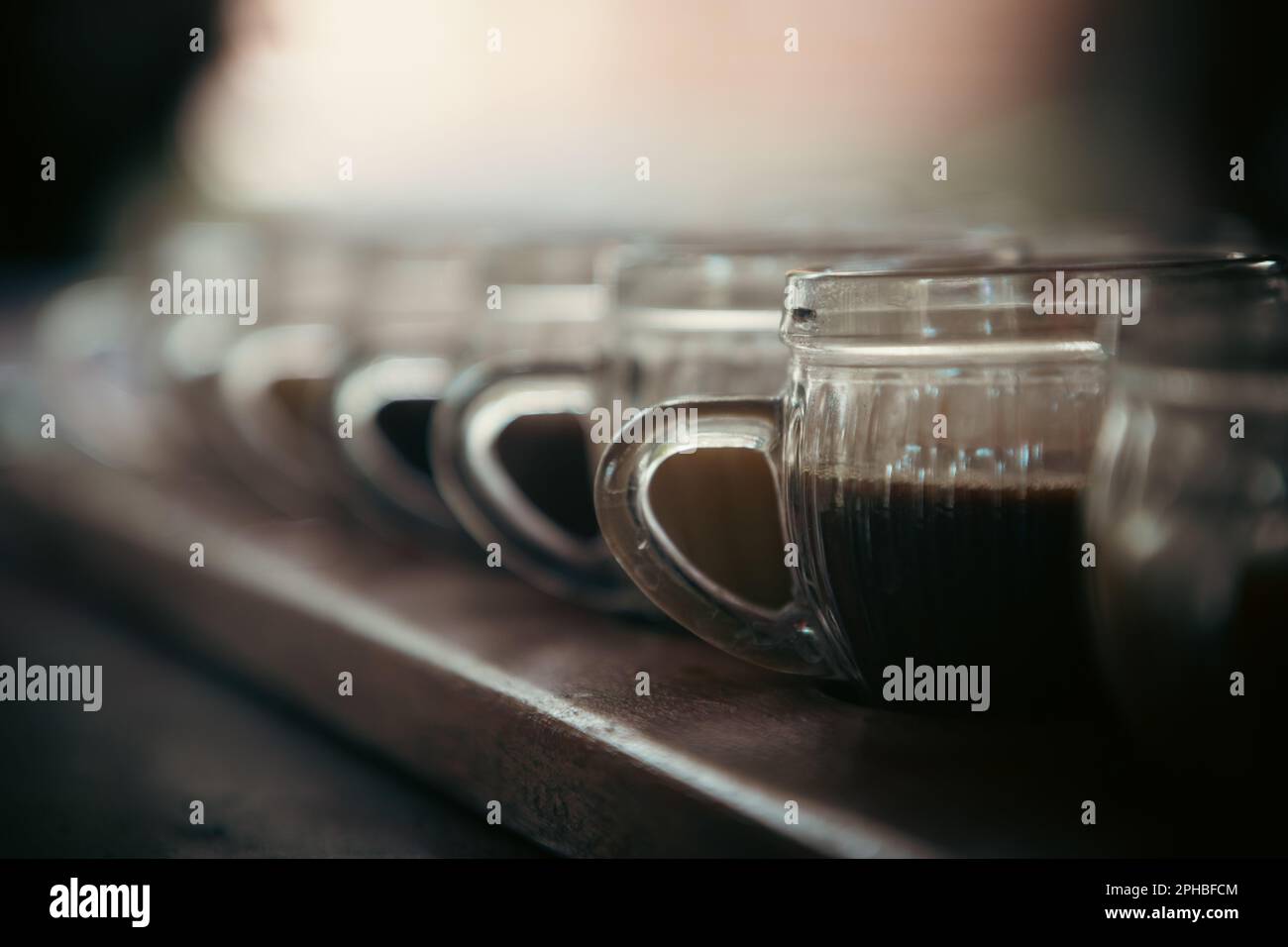 Una serie di bicchieri riempiti con varie bevande allineate ordinatamente su un tavolo Foto Stock