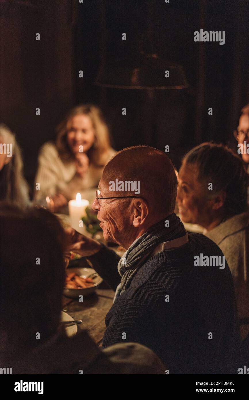 Uomo anziano con gli amici che si diverse alla cena a lume di candela Foto Stock