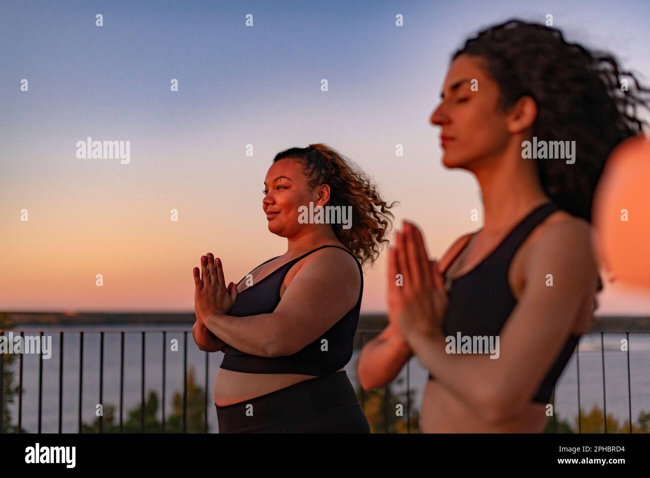 Donna sorridente con le mani afferrate da un'amica al tramonto Foto Stock