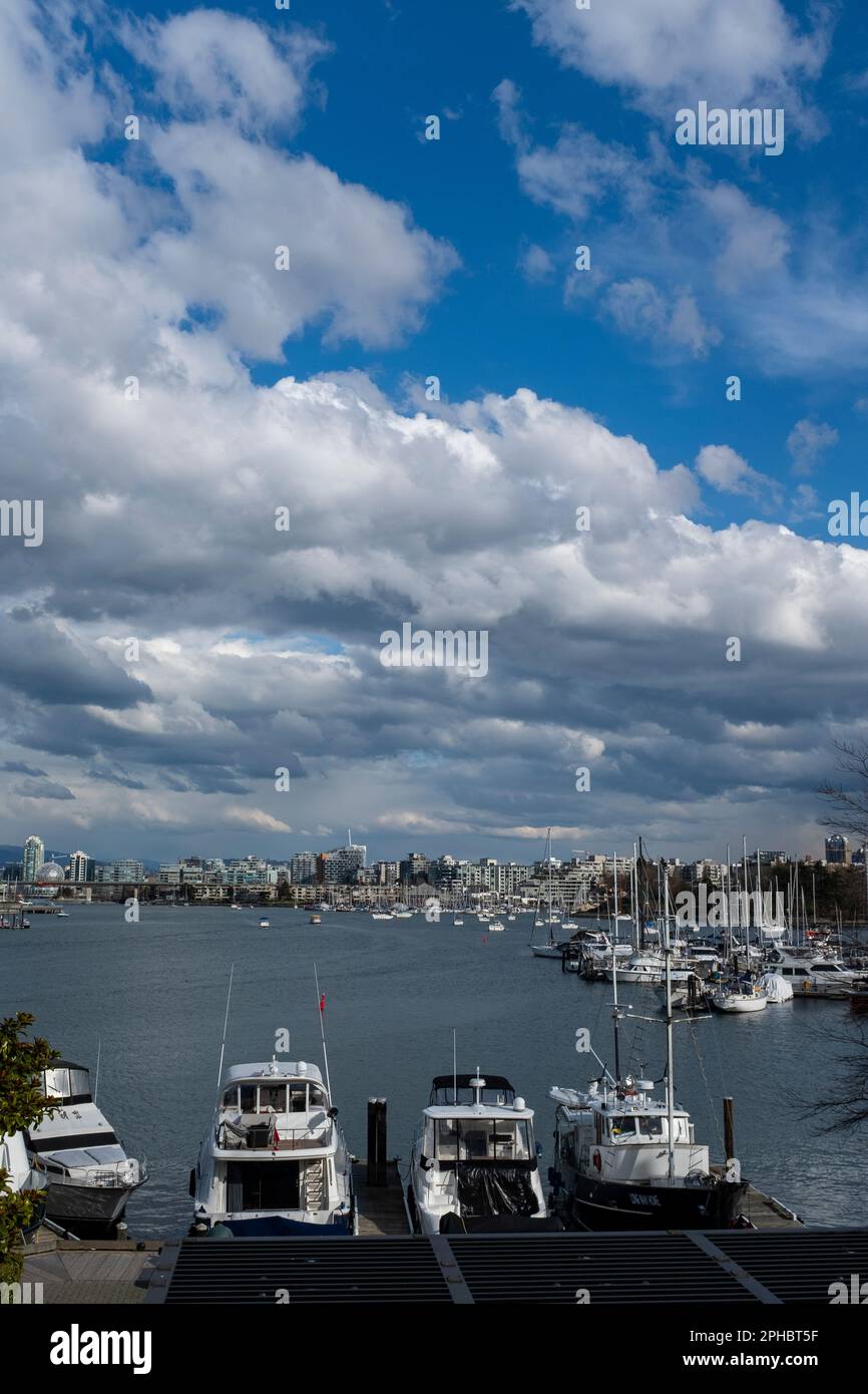 Nuvole di pioggia e cielo blu brillante su grattacieli e barche ormeggiate a False Creek vicino a Granville Island a Vancouver, British Columbia Foto Stock