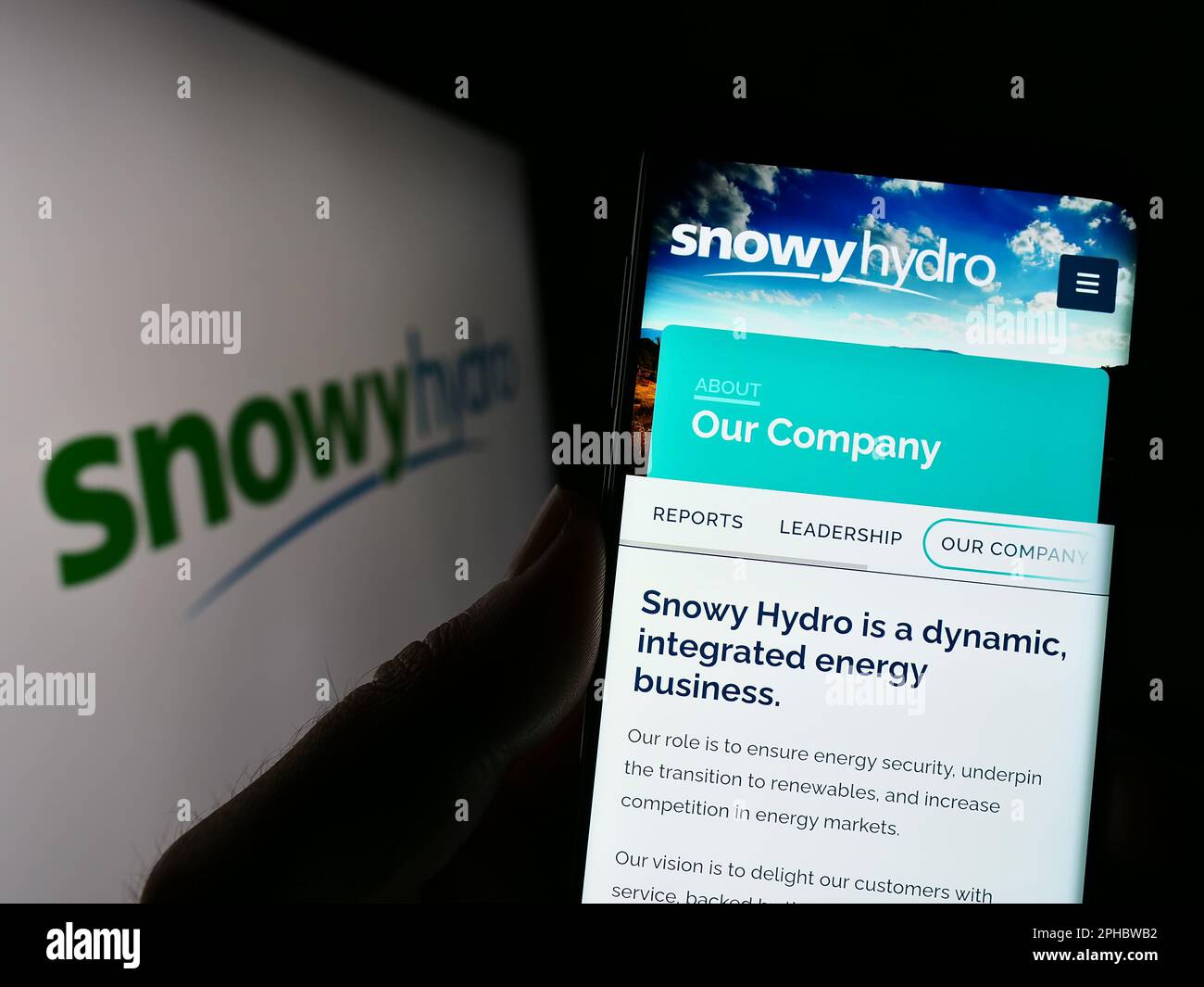 Persona che tiene il cellulare con la pagina web della società australiana di energia Snowy Hydro Limited sullo schermo con il logo. Messa a fuoco al centro del display del telefono. Foto Stock