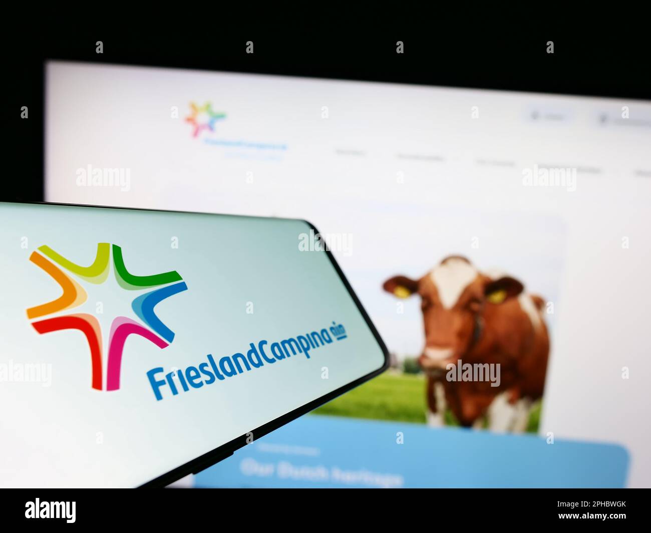 Telefono cellulare con il logo della società Koninklijke FrieslandCampina NV sullo schermo di fronte al sito web aziendale. Messa a fuoco al centro del display del telefono. Foto Stock