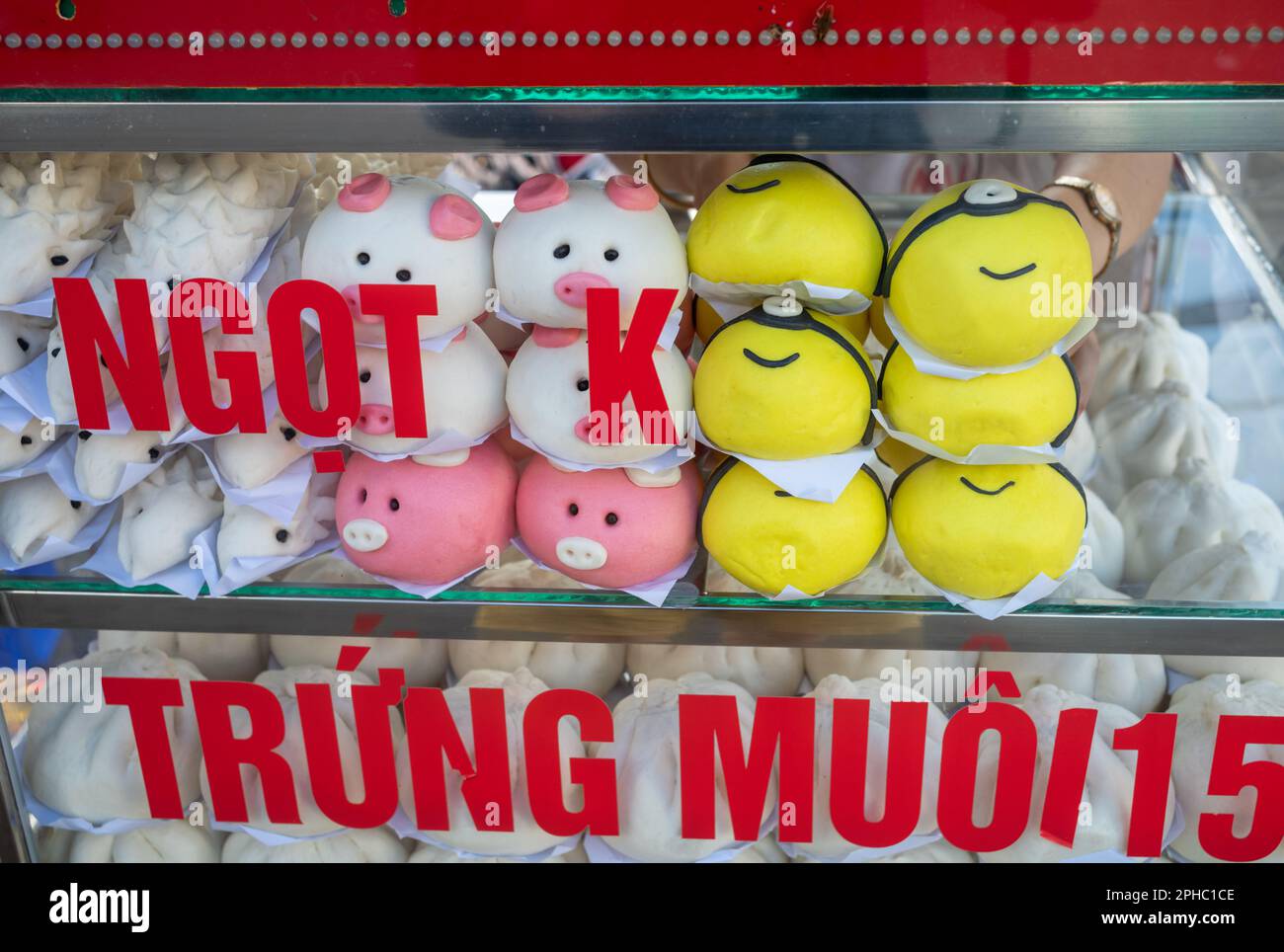 Armadietti di vetro riscaldati pieni di panini dolci vietnamiti al vapore bao a forma di peppa e un minion in vendita al mercato centrale di PLEIKU i. Foto Stock