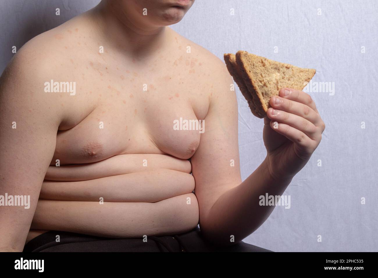 Un ragazzo caucasico in sovrappeso che mangia un panino Foto Stock