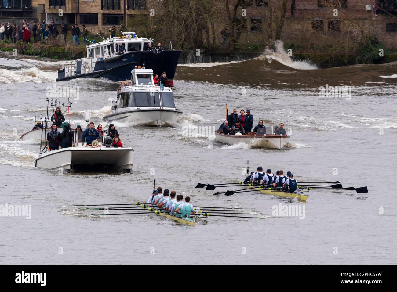 Gara di barche 2023. Cambridge conduce Oxford verso il traguardo nella gara maschile, con la successiva flotilla che crea il lavaggio contro il fiume. Attiva Foto Stock