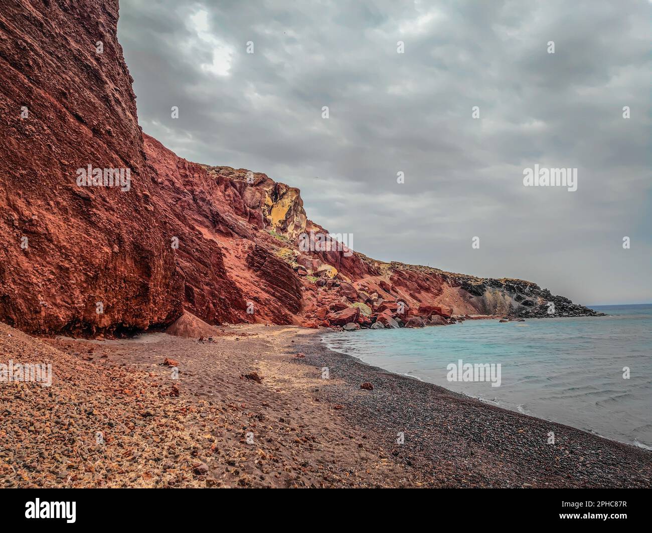 La famosa spiaggia rossa, Kokkini Paralia nell'isola di Santorini, Grecia. Spiaggia di sabbia rossa unica in una giornata nuvolosa Foto Stock