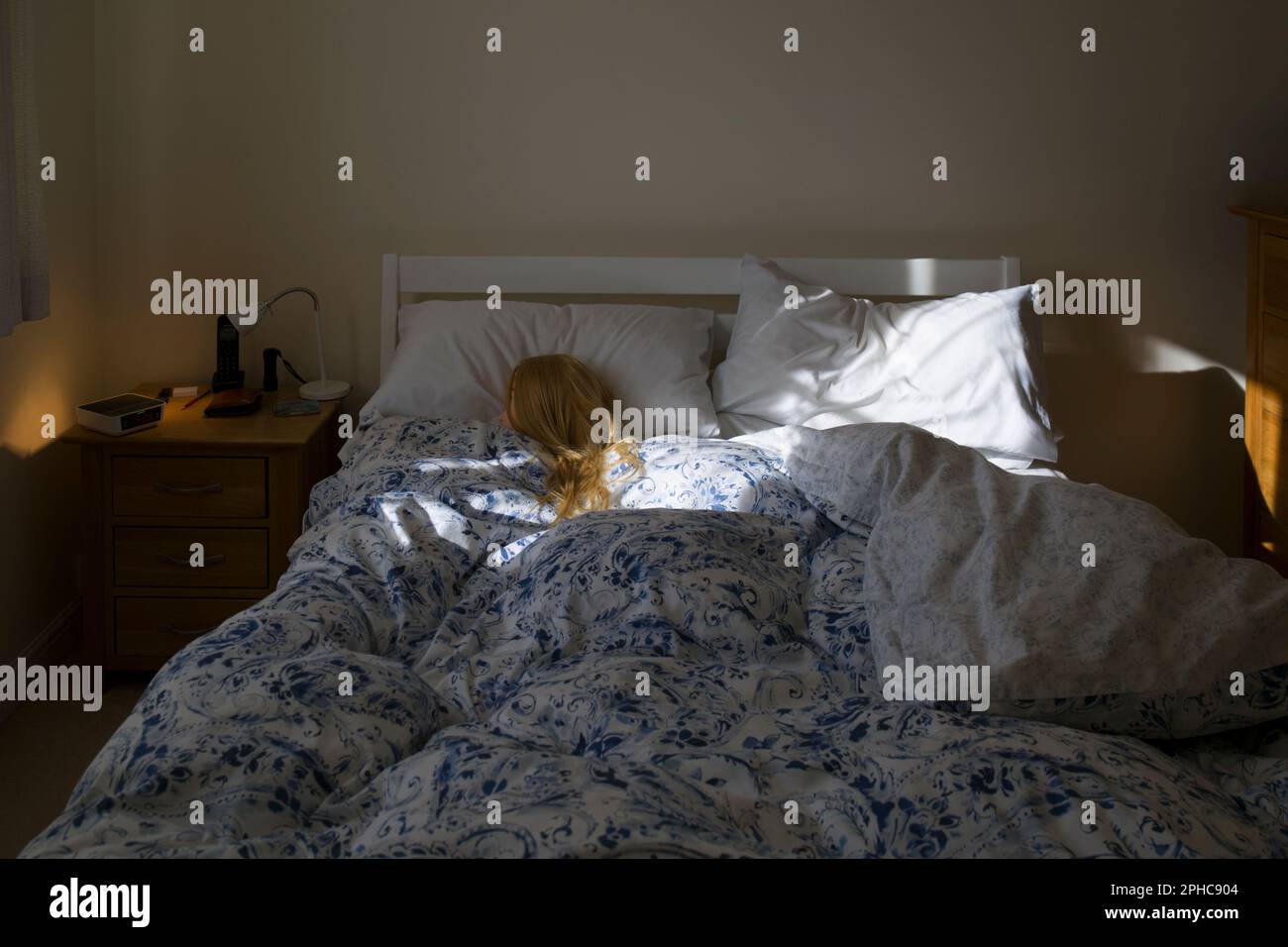 Donna Bionda (manichino) che dorme in Letto illuminato da mattina sole Foto Stock