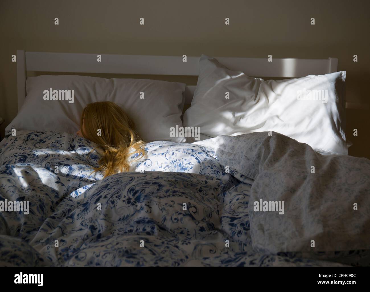 Donna Bionda (manichino) che dorme in Letto illuminato da mattina sole Foto Stock