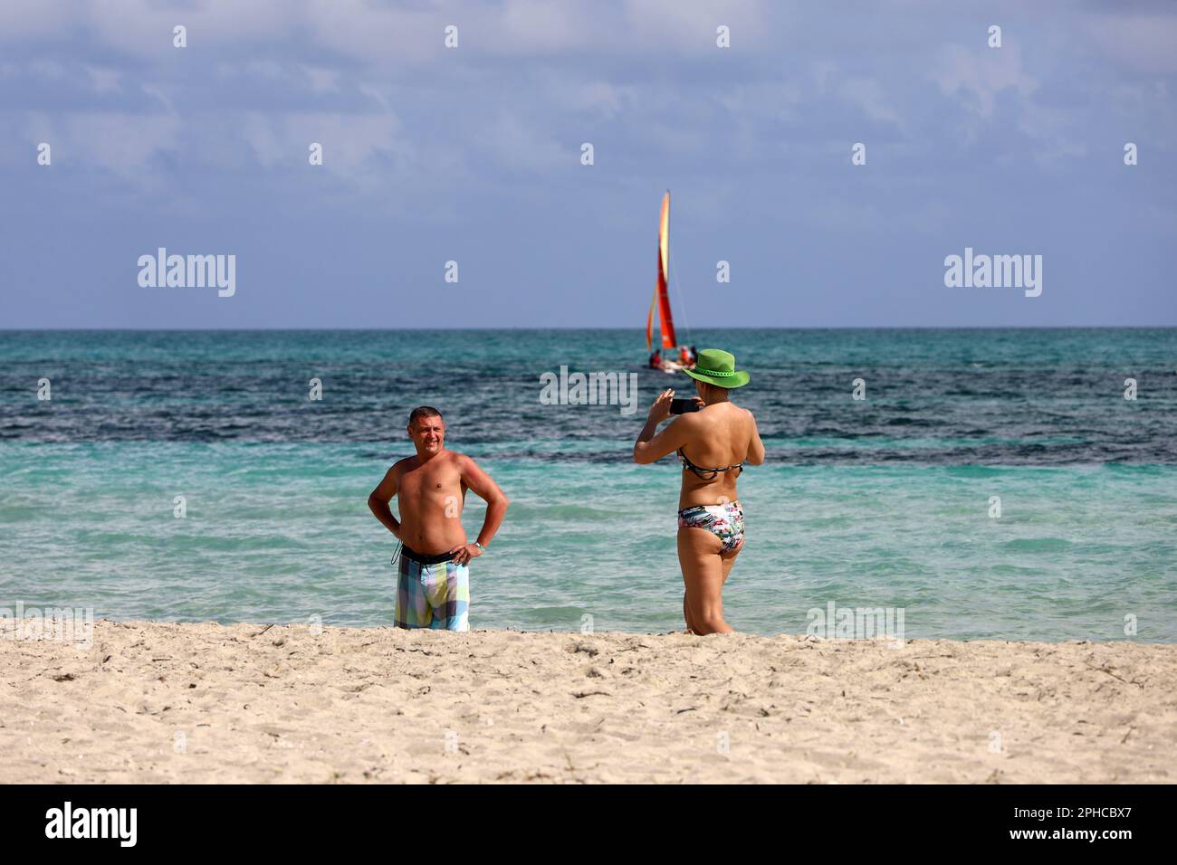 Donna che fotografa un uomo su smartphone su una spiaggia di sabbia tropicale. Fotografare in costa oceanica, vacanze e viaggi Foto Stock