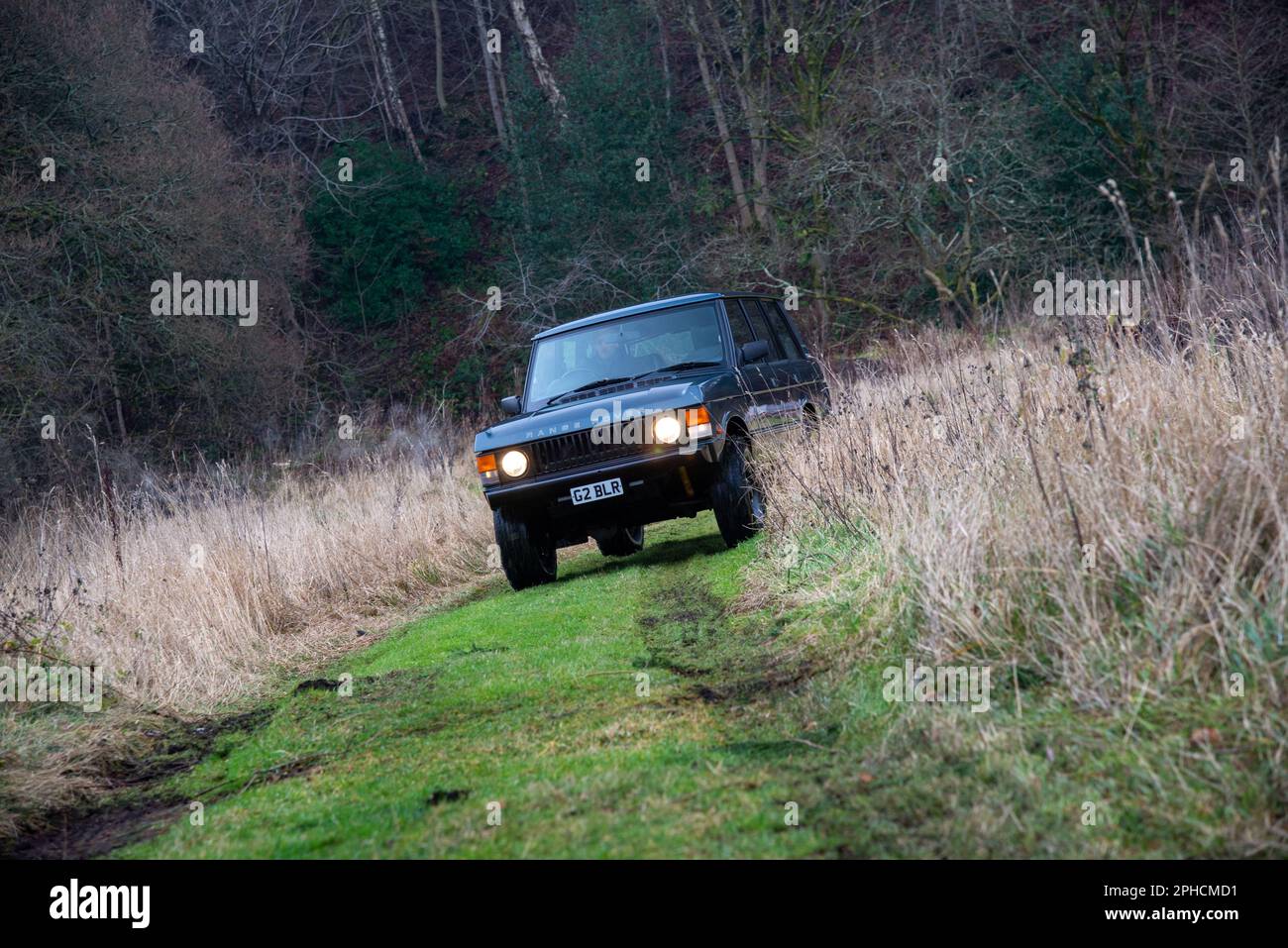 Range Rover Classic guida su una pista di campagna con i fari accesi in un giorno d'autunno Foto Stock