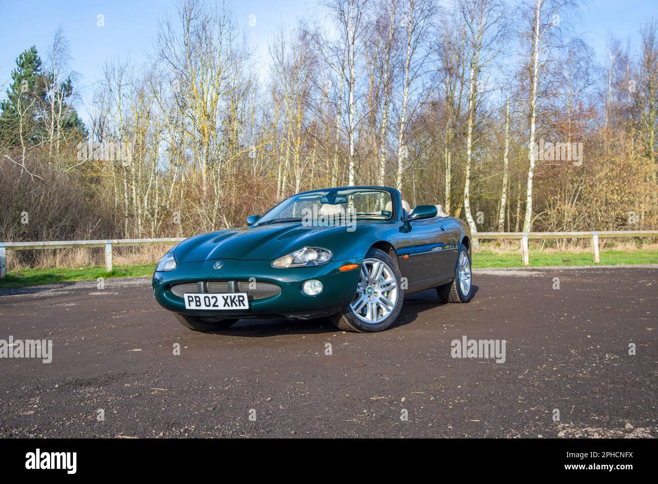 Jaguar XK-R parcheggiata su un'auto sterrata [ark in woodland in un luminoso giorno d'autunno Foto Stock
