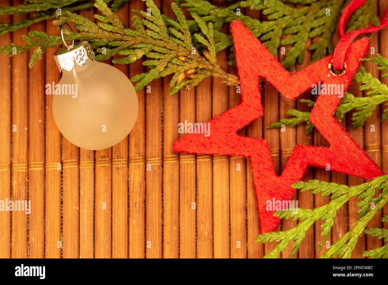 Festa con Stella rossa e decorazione in vetro smerigliato con rami verdi su una superficie in legno Foto Stock