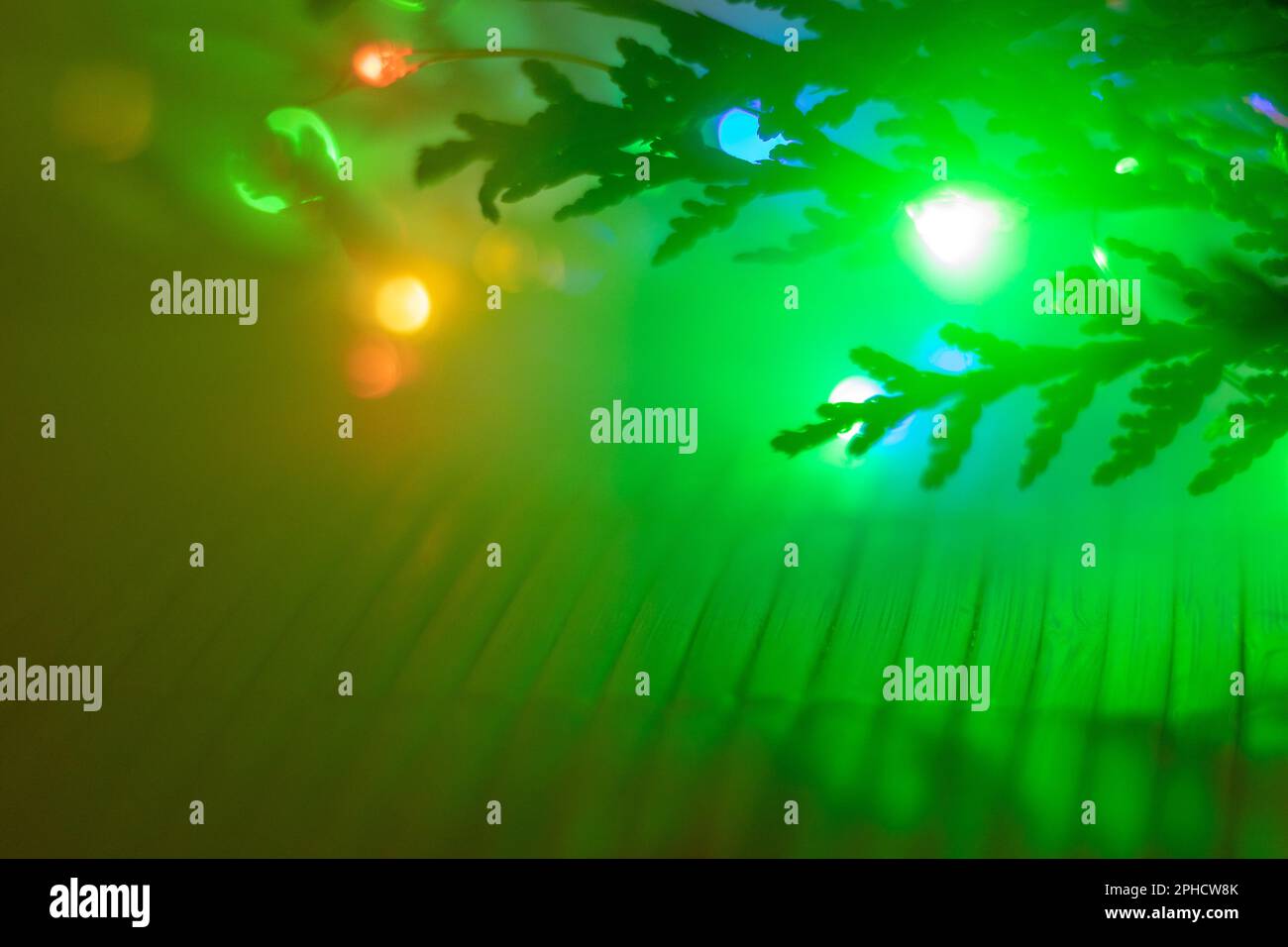 Ramo verde festivo con luci bokeh colorate in un caldo bagliore natalizio Foto Stock