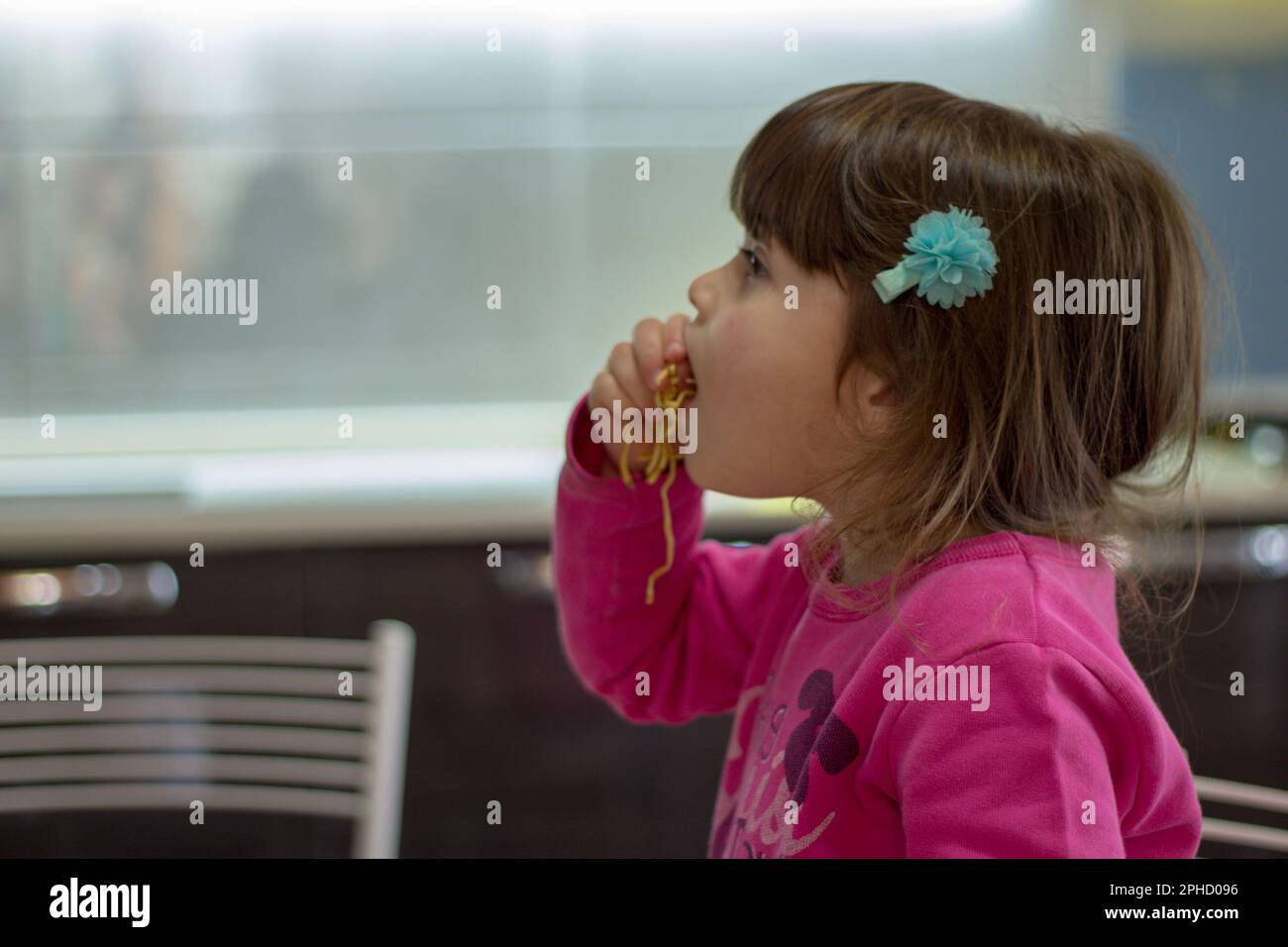 Immagine di una adorabile bruna che mangia spaghetti con le mani. Foto Stock