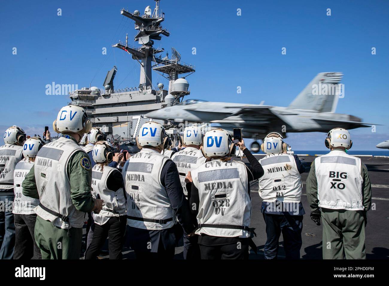 230323-N-EL850-1221 MAR TIRRENO (23 marzo 2023) leadership militare e civile italiana dalla Sicilia e dagli Stati Uniti Consolato di Napoli guarda un aereo F/A-18E Super Hornet, attaccato allo Strike Fighter Squadron (VFA) 136, atterrare sul ponte di volo della portaerei di classe Nimitz USS George H.W. Boccola (CVN 77), 23 marzo 2023. Carrier Air Wing (CVW) 7 è la componente offensiva di Carrier Strike Group (CSG) 10 e George H.W. Boccola CSG. Gli squadroni del CVW-7 sono VFA-143, VFA-103, VFA-86, VFA-136, vettore aereo Early Warning Squadron (VAW) 121, attacco elettronico Squadrone Foto Stock