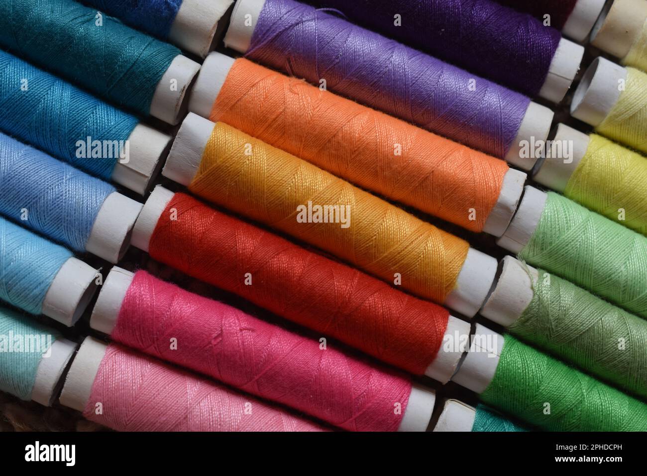 Spole di filo da cucire in una varietà di colori vibranti. Foto Stock