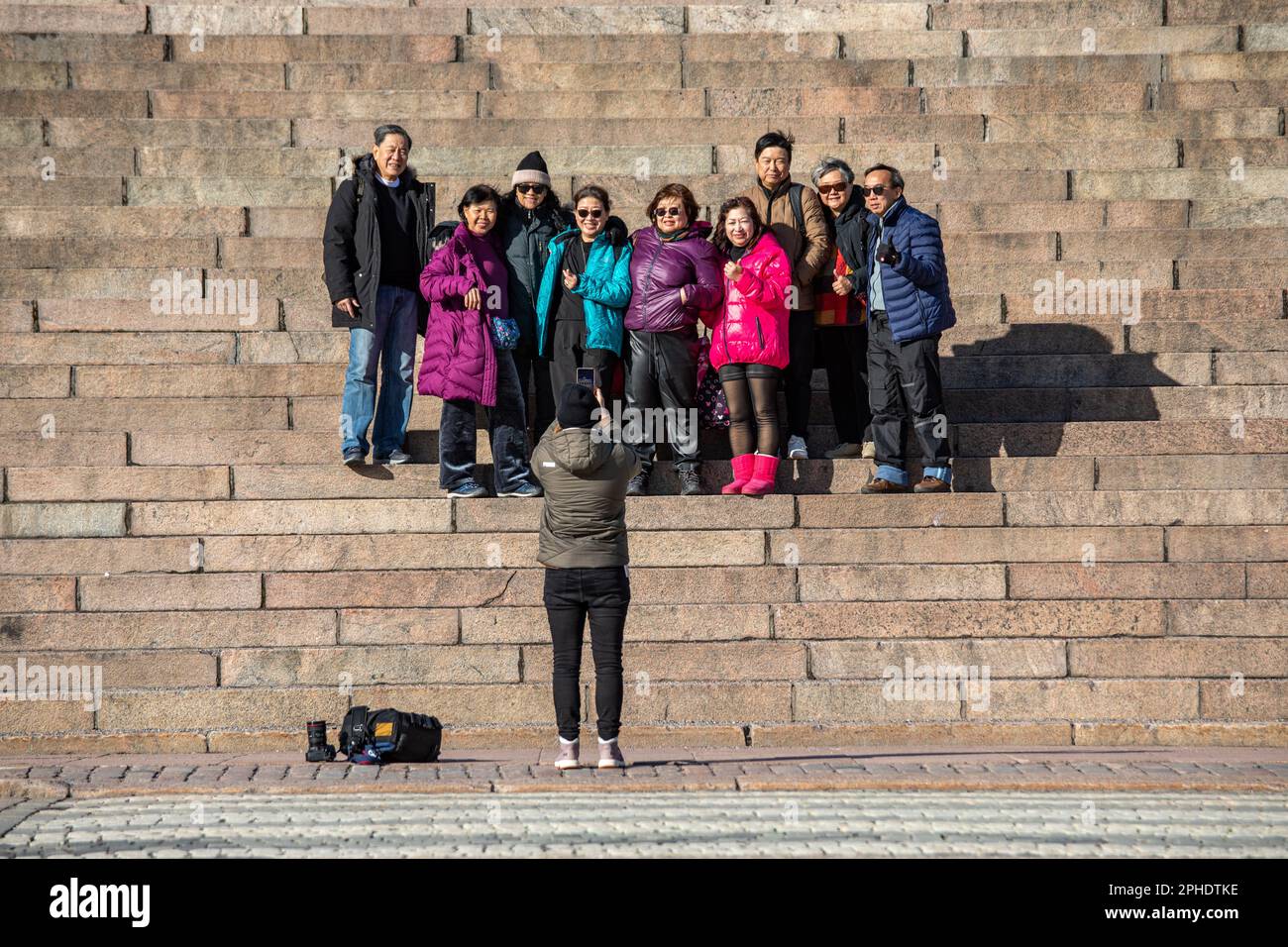 Turisti asiatici in posa per una foto di gruppo su Helsinki Cathedral Steps in una soleggiata giornata di primavera nel quartiere Kruununhaka di Helsinki, Finlandia Foto Stock
