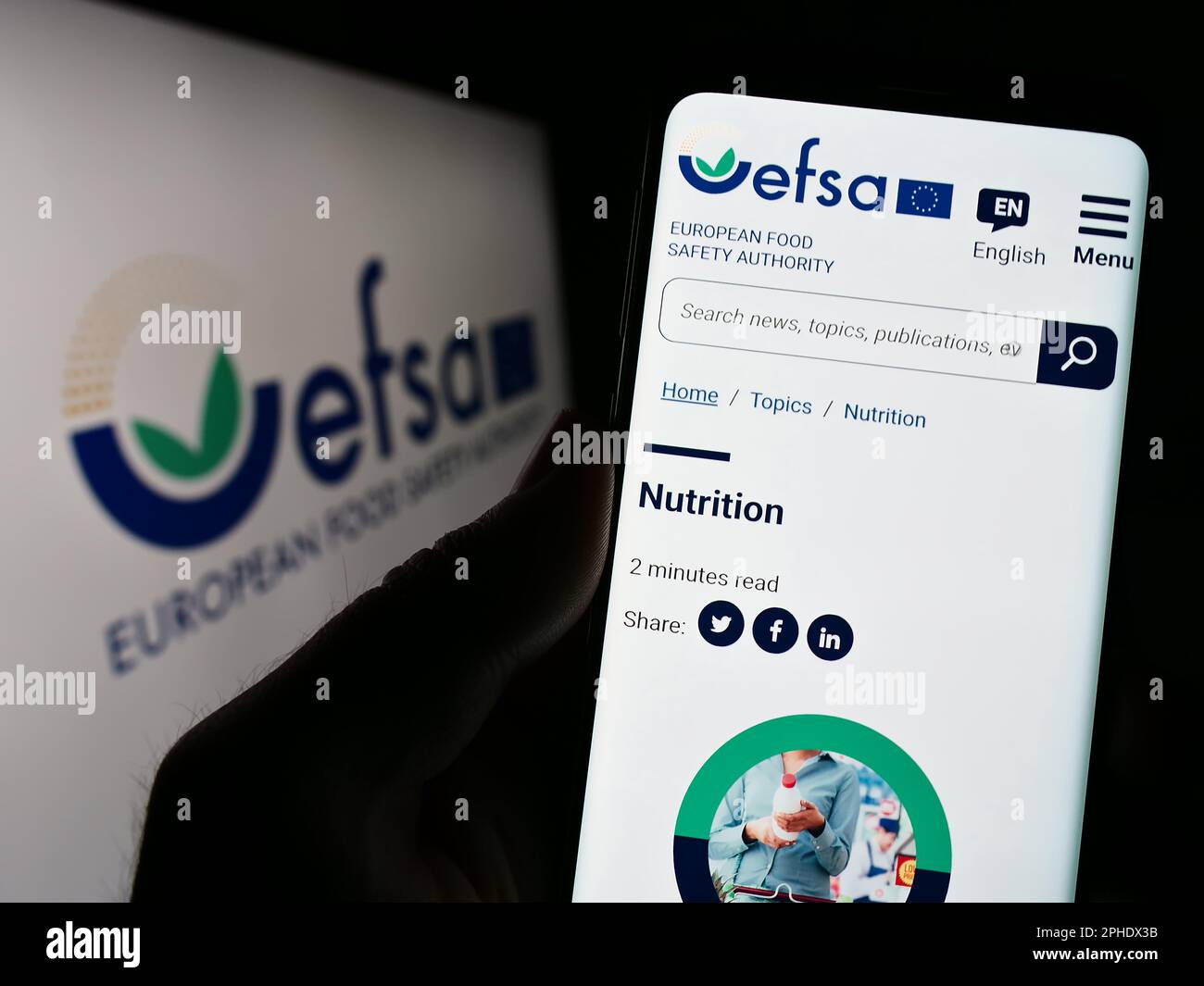 Persona che tiene il cellulare con la pagina web dell'Agenzia europea per la sicurezza alimentare (EFSA) sullo schermo con il logo. Messa a fuoco al centro del display del telefono. Foto Stock