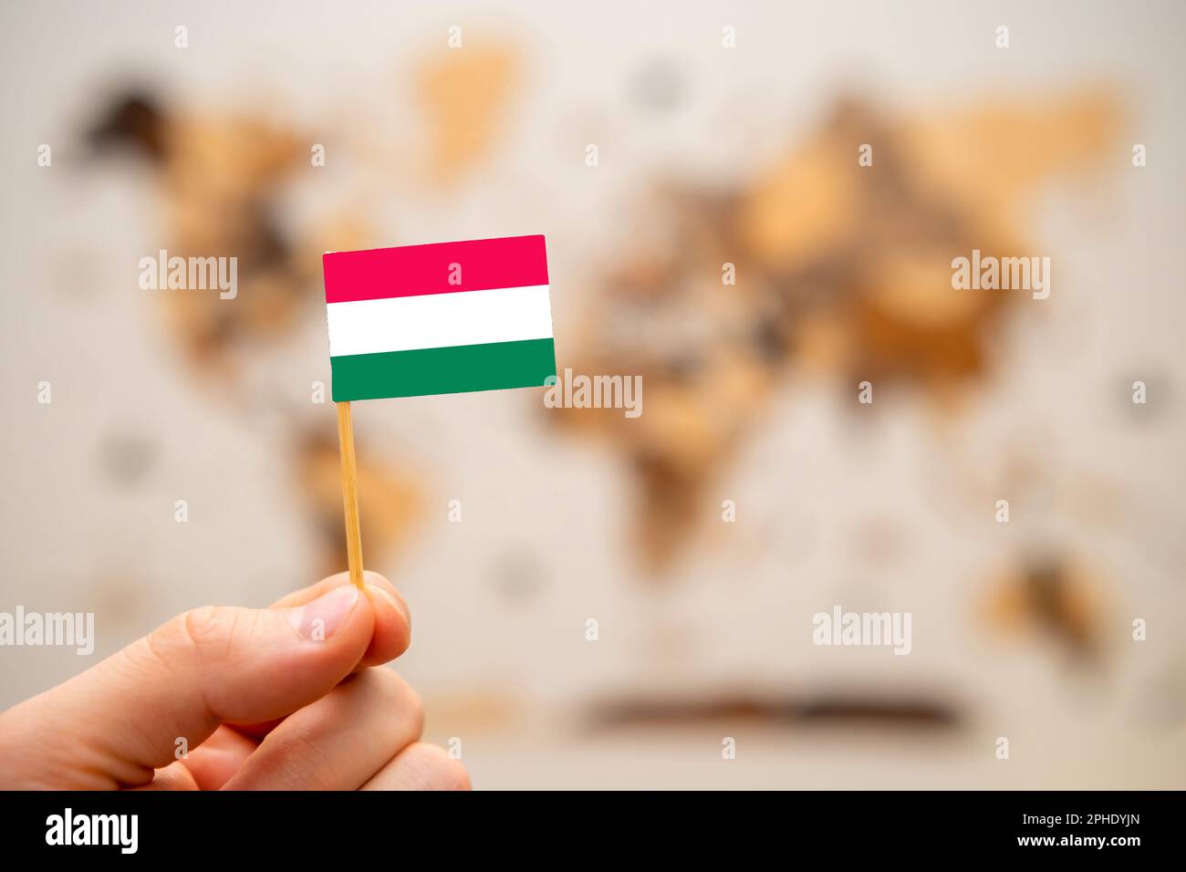 Bandiera dell'Ungheria a mans mano sullo sfondo della mappa del mondo in legno. Economia globale e concetto geopolitico. Foto Stock
