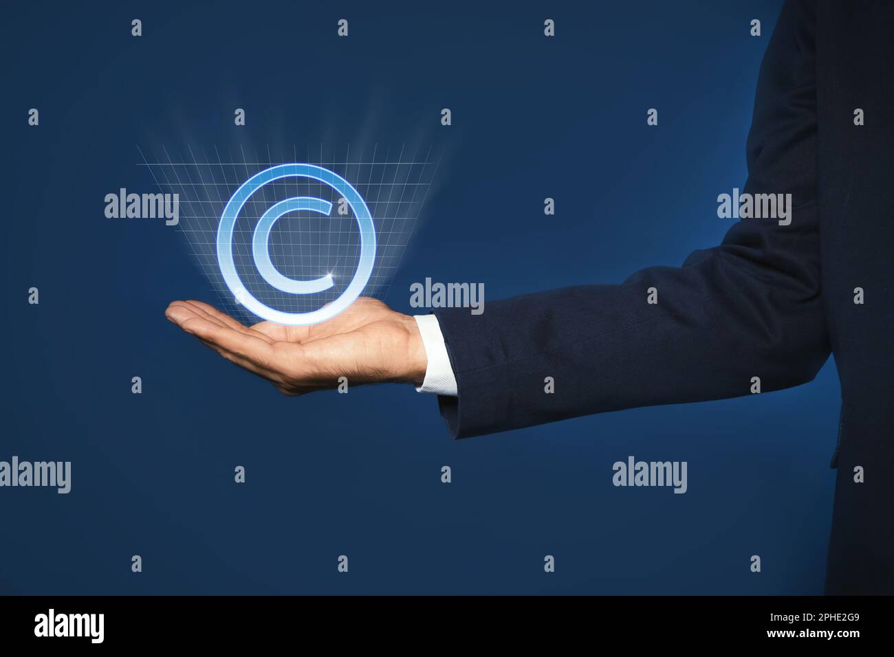 Uomo che tiene l'icona virtuale del simbolo di copyright su sfondo blu, primo piano Foto Stock