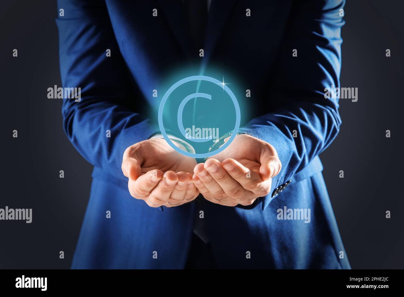 Uomo che tiene l'icona virtuale del simbolo di copyright su sfondo scuro, primo piano Foto Stock
