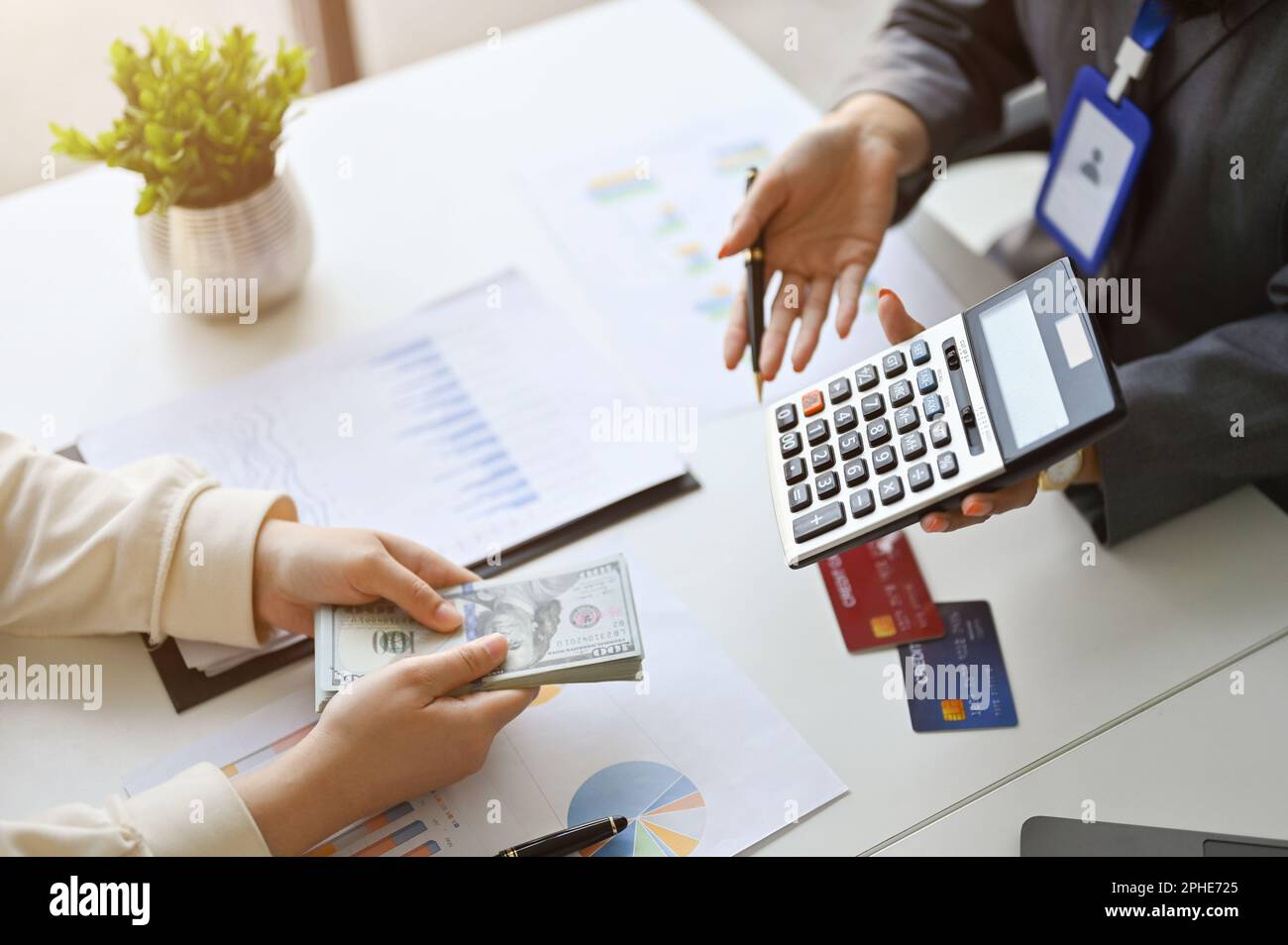 Vista dall'alto di un banchiere o consulente finanziario professionista che parla e mostra il margine di profitto sulla calcolatrice a un cliente. Foto Stock