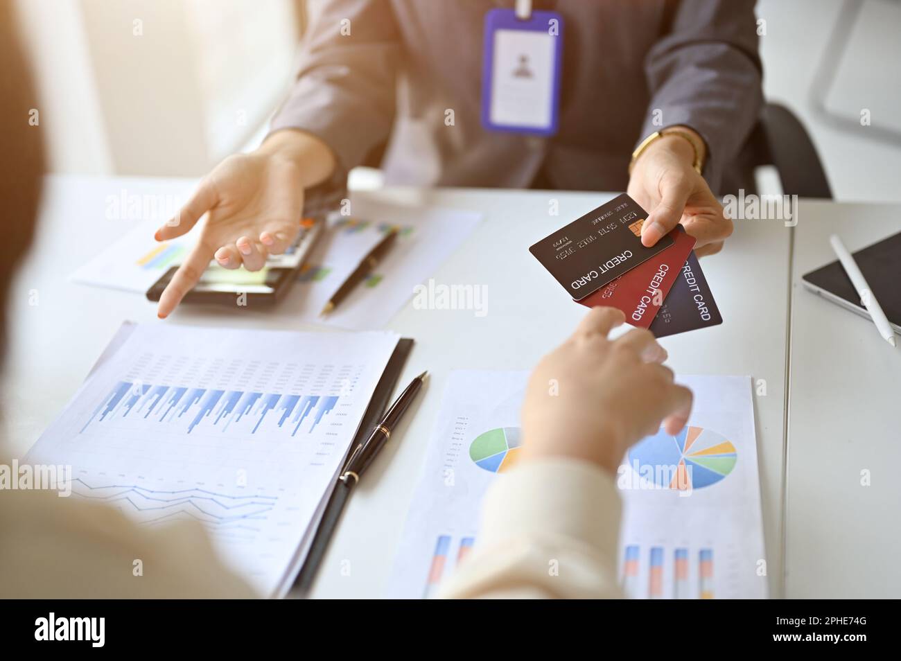 Immagine ritagliata di un banchiere femminile asiatico professionale che mostra vari tipi di carte di credito a un cliente durante la riunione. conc. finanziario e commerciale Foto Stock