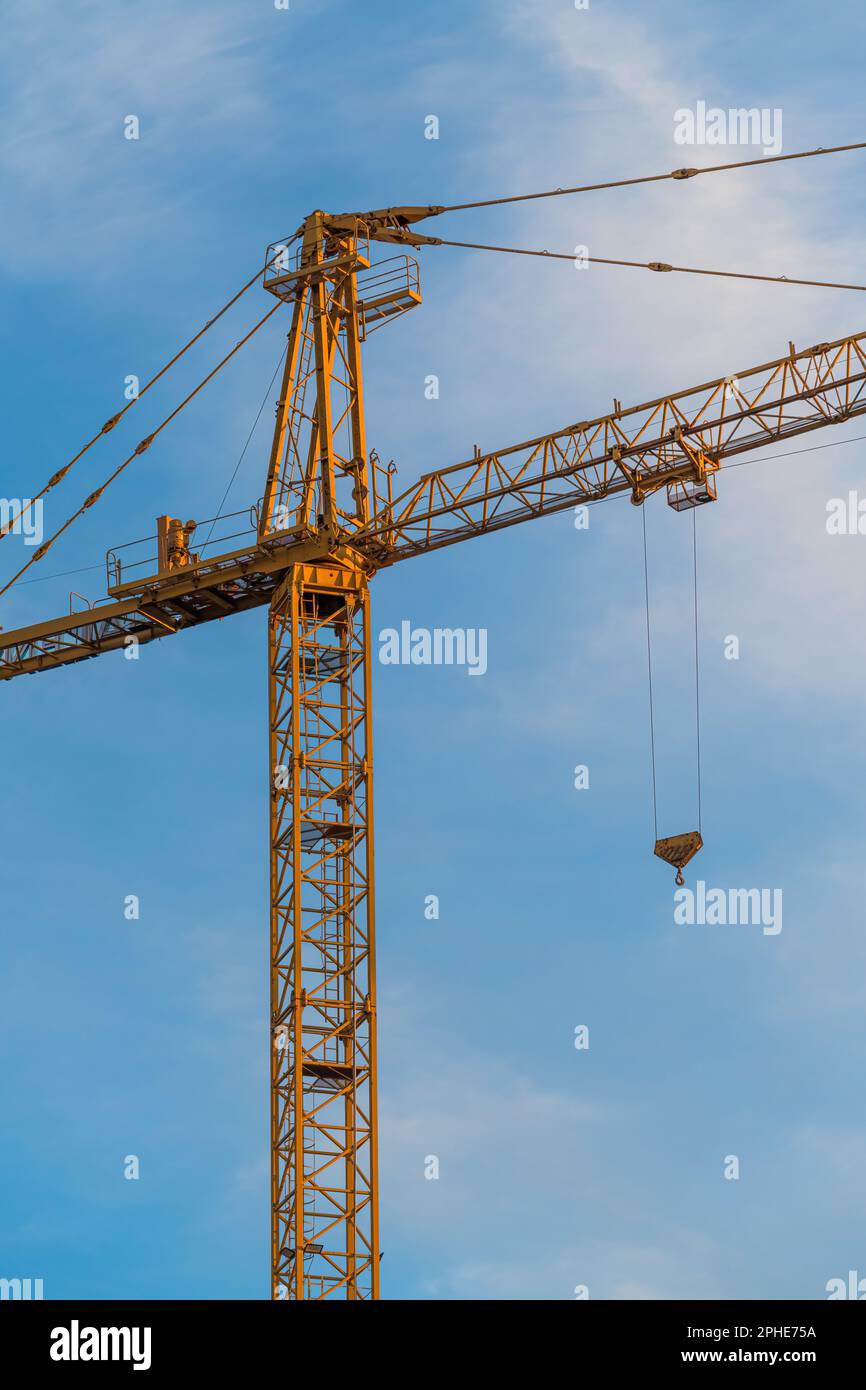 Macchine gru industriali gialle in cantiere contro il cielo blu Foto Stock