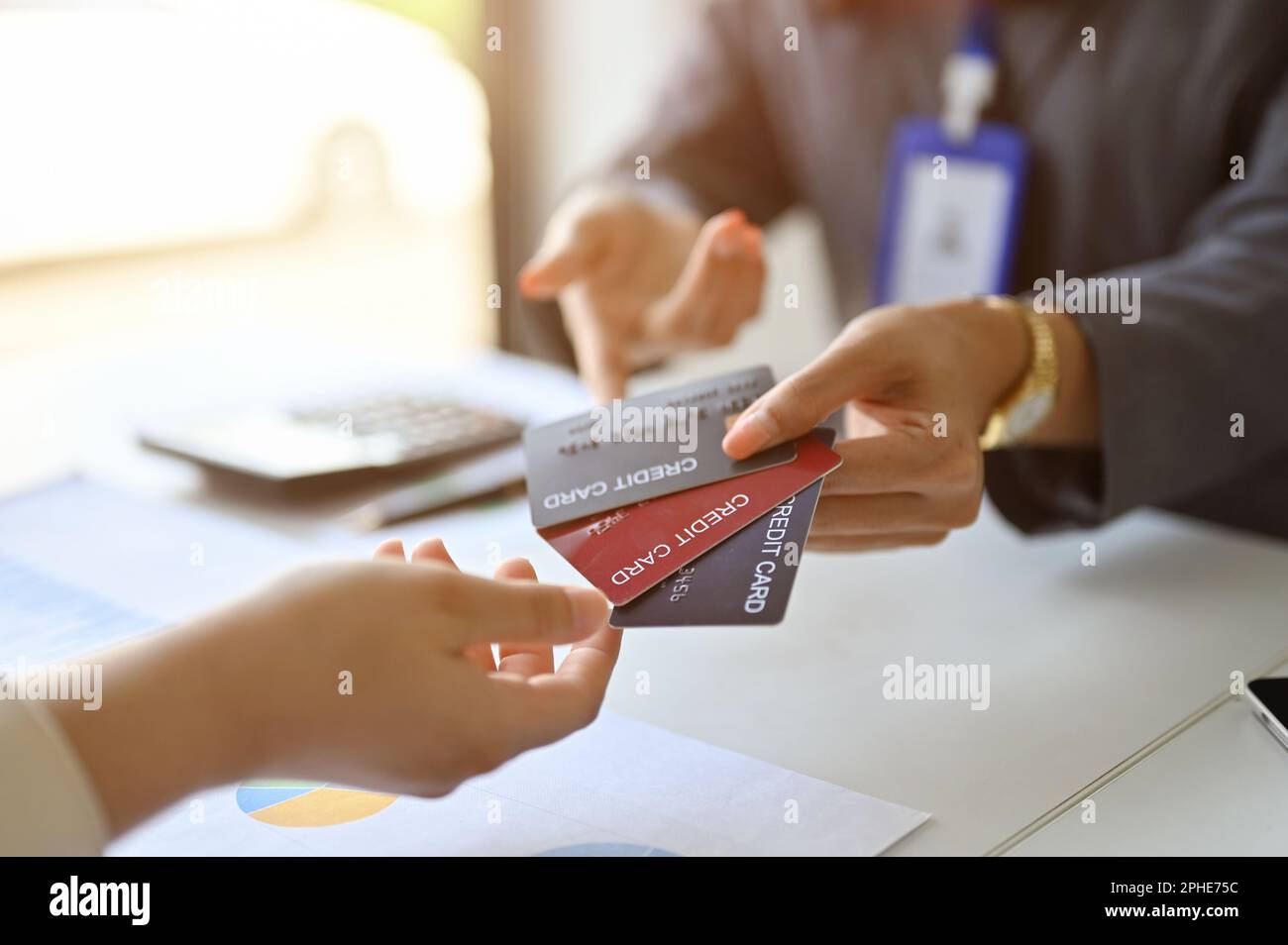 Immagine ritagliata di un banchiere femminile asiatico professionale che mostra vari tipi di carte di credito a un cliente durante la riunione presso la banca. Foto Stock