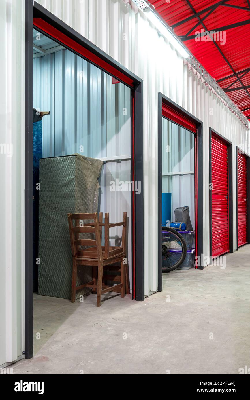 Corridoio dell'unità di self-storage con porte rosse. Unità di stoccaggio a noleggio Foto Stock
