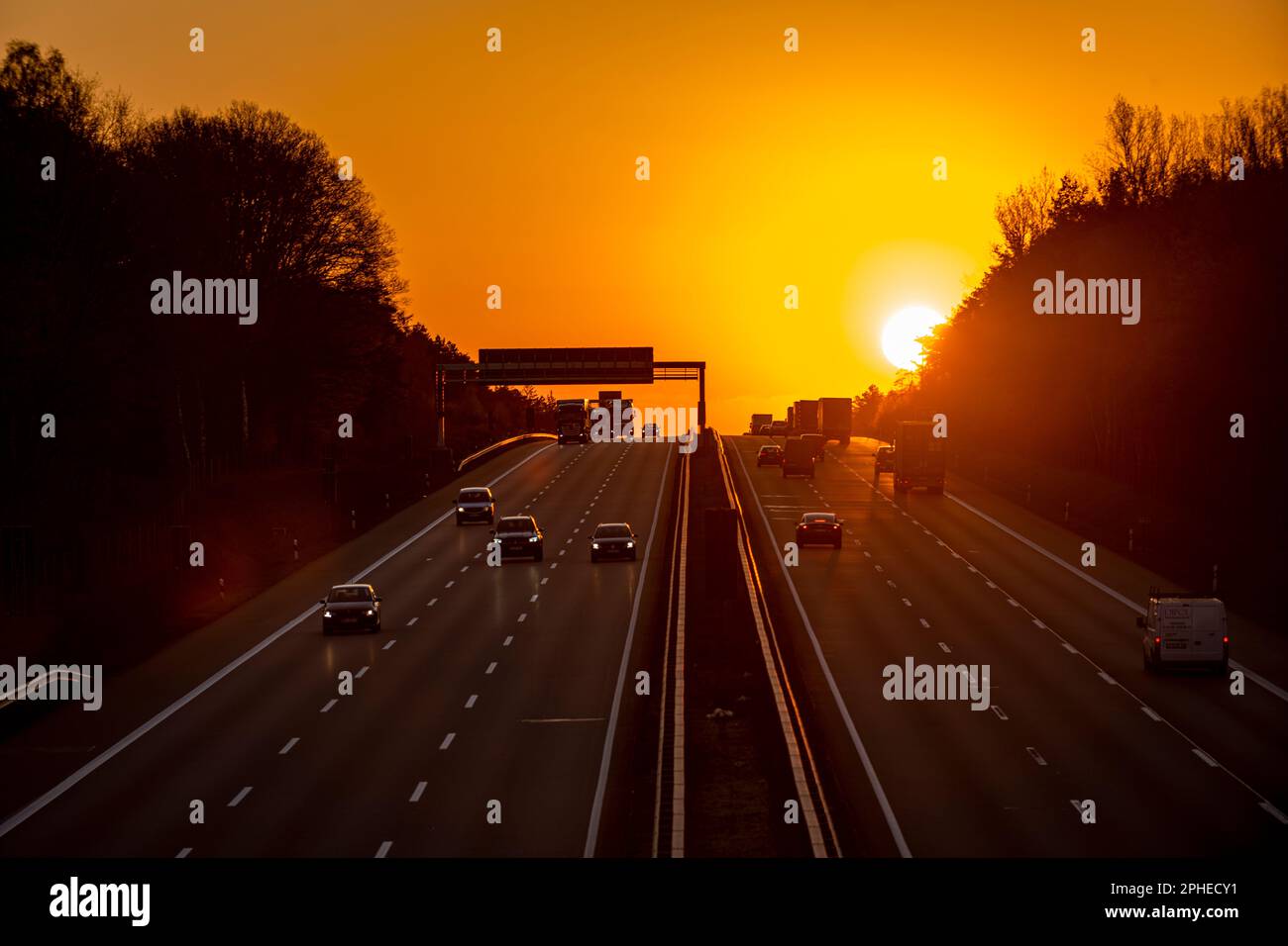 Vista aerea di un'autostrada durante il tramonto. Diverse automobili circolano sulle corsie di una strada illuminata dalla luce del sole. Foto Stock