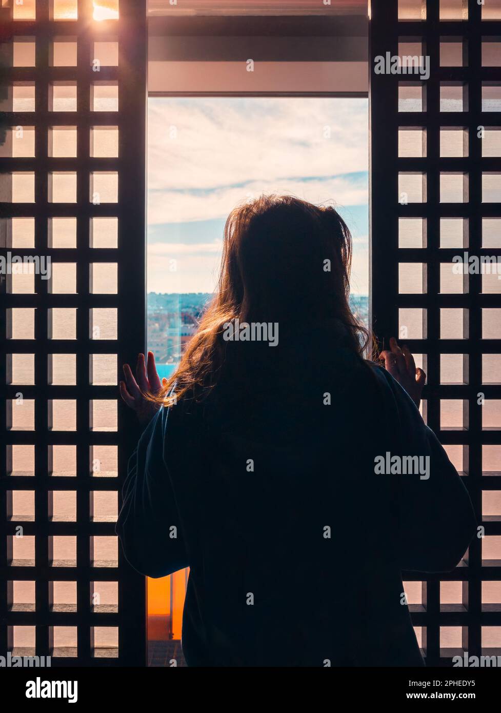 Vista posteriore di donne irriconoscibili in abiti casual in piedi vicino alla finestra e guardare la città attraverso il vetro Foto Stock