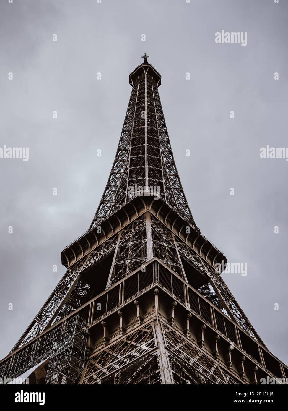 Un'immagine dall'angolo basso dell'iconica Torre Eiffel a Parigi, in Francia, sullo sfondo di cieli grigi e nuvolosi Foto Stock