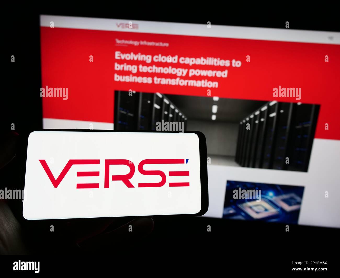 Persona che tiene il cellulare con il logo della società indiana Verse Innovation Pvt. Ltd. Sullo schermo di fronte al sito web aziendale. Messa a fuoco sul display del telefono. Foto Stock