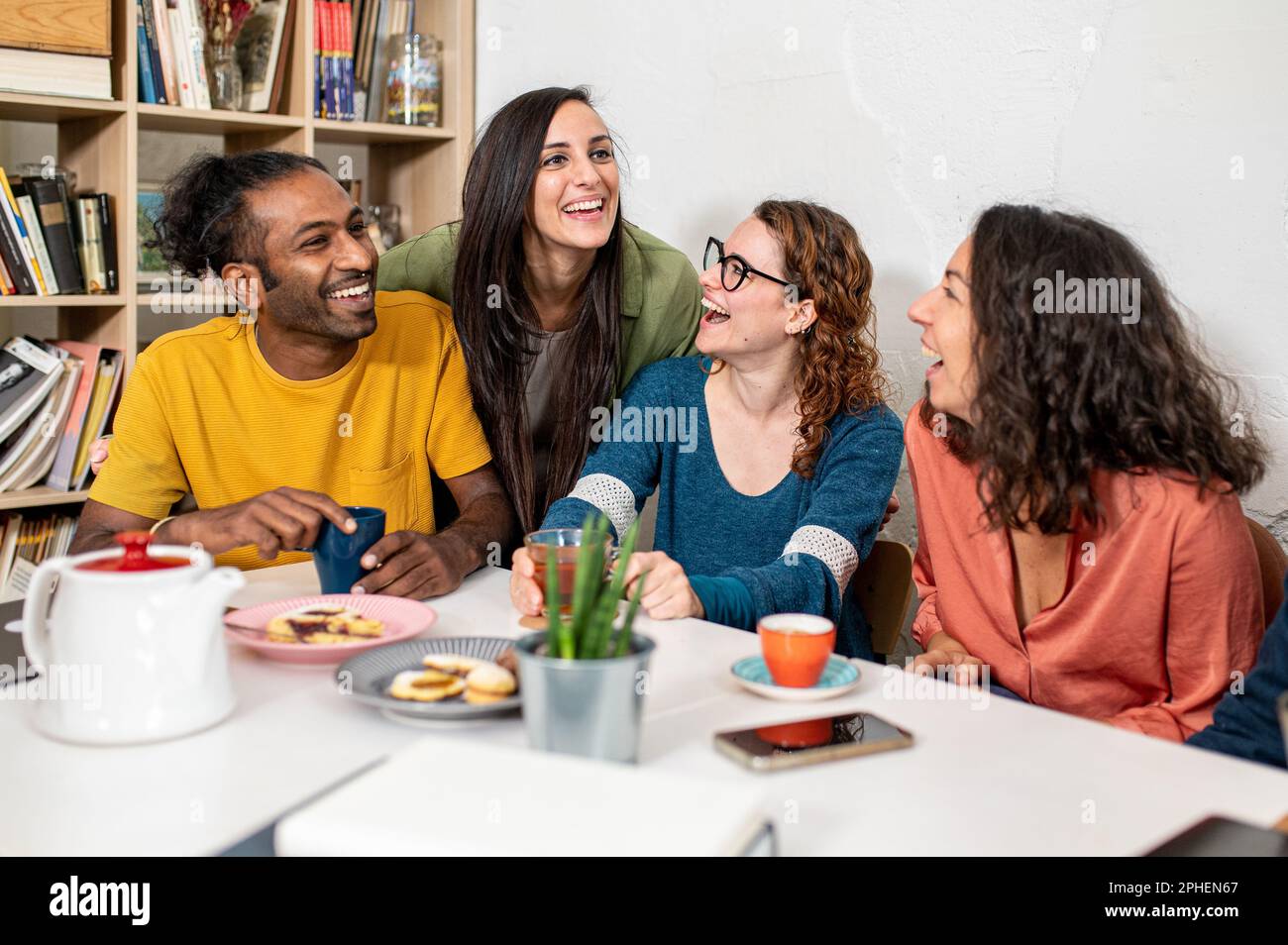 Amici che studiano insieme in una caffetteria, la gente ha un po 'di spuntino per una pausa, gruppo multirazziale divertirsi al coperto Foto Stock