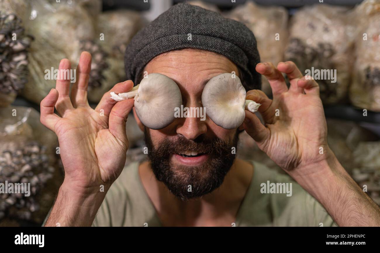 Ritratto di un giovane ispanico che tiene il fungo di ostriche davanti agli occhi. Foto Stock