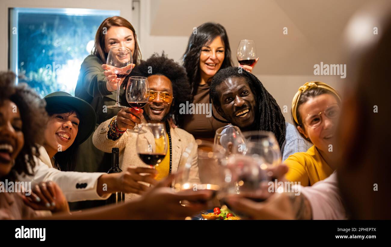 Una persona irriconoscibile riceve i saluti dai suoi amici e dalla sua famiglia durante una cena vegetariana, gente felice che brinda insieme sorridendo per alcuno Foto Stock