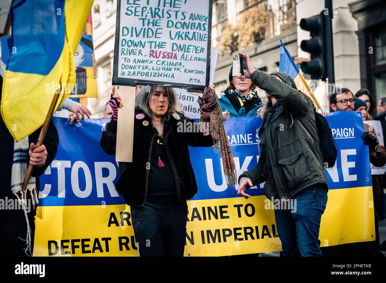 Un gruppo eterogeneo di persone che trasportano bandiere ucraine e protestano contro la guerra in Ucraina Foto Stock