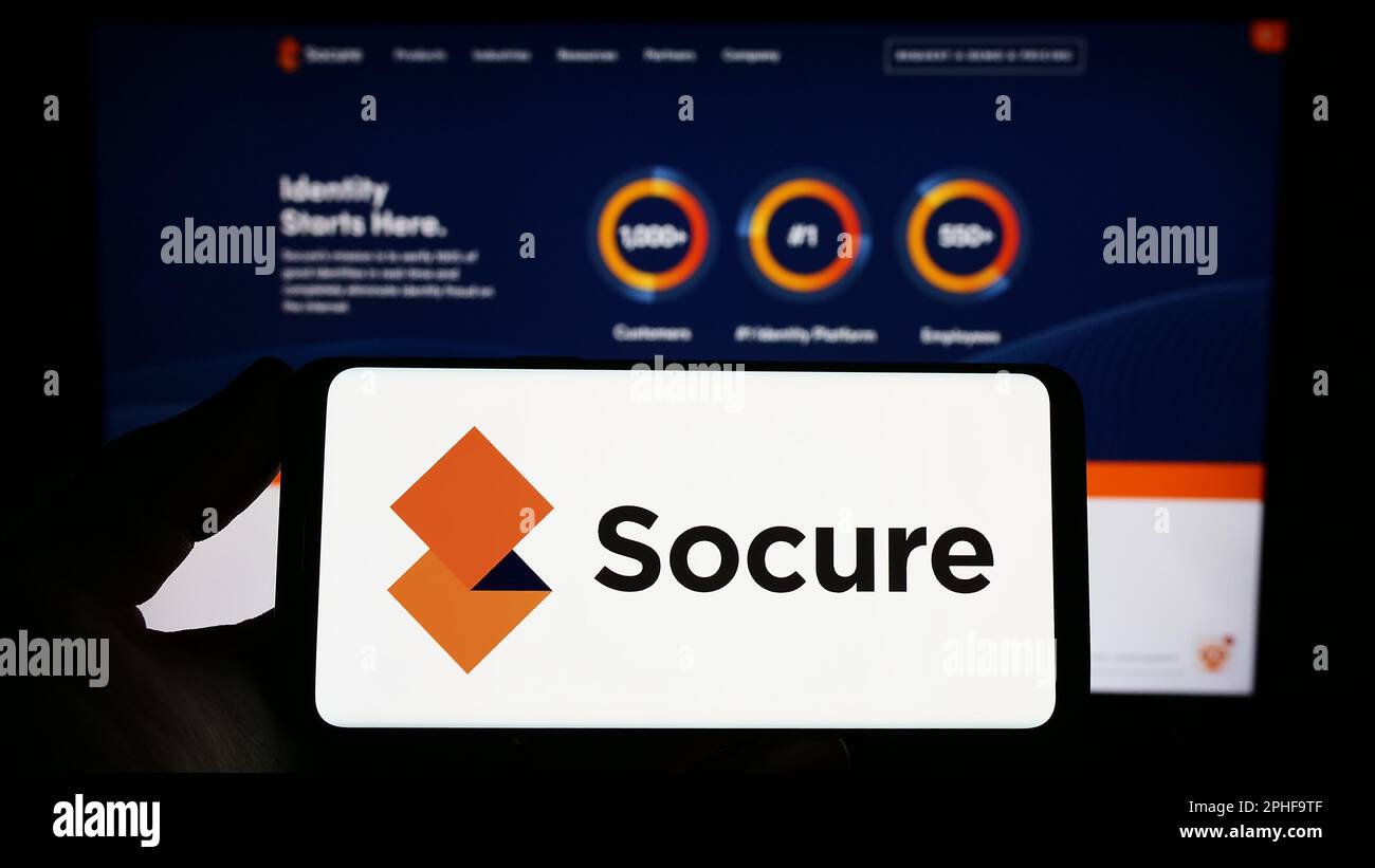Persona che detiene uno smartphone con il logo della società statunitense di verifica dell'identità Socure Inc. Sullo schermo di fronte al sito Web. Messa a fuoco sul display del telefono. Foto Stock