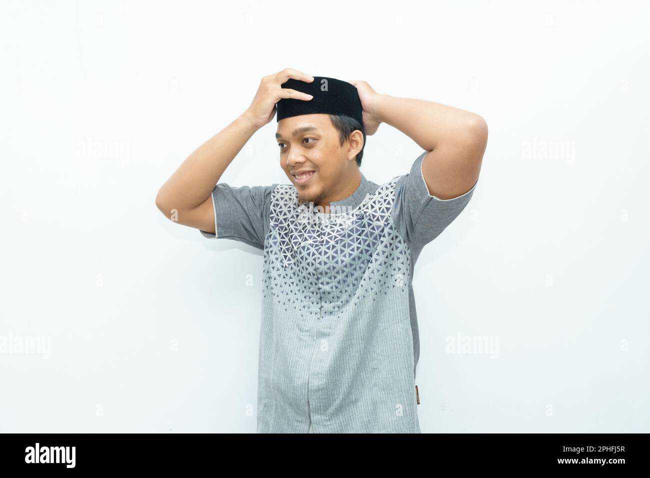 L'uomo musulmano asiatico indonesiano sorridente indossa un cappello nero chiamato peci o songkok Foto Stock