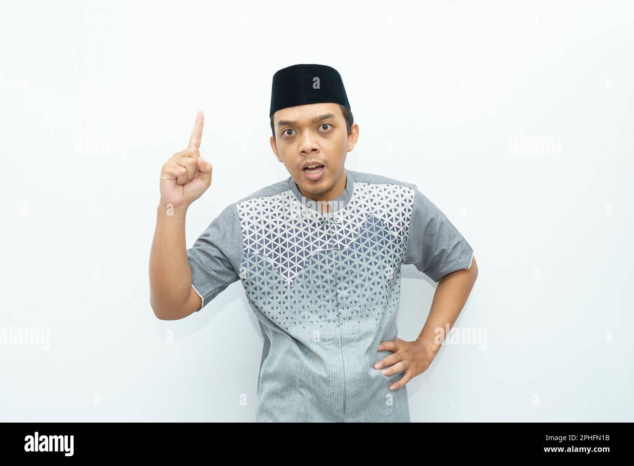 Ritratto dell'uomo musulmano asiatico indonesiano che mostra il dito verso l'alto, che parla, che dà un gesto di avvertimento Foto Stock