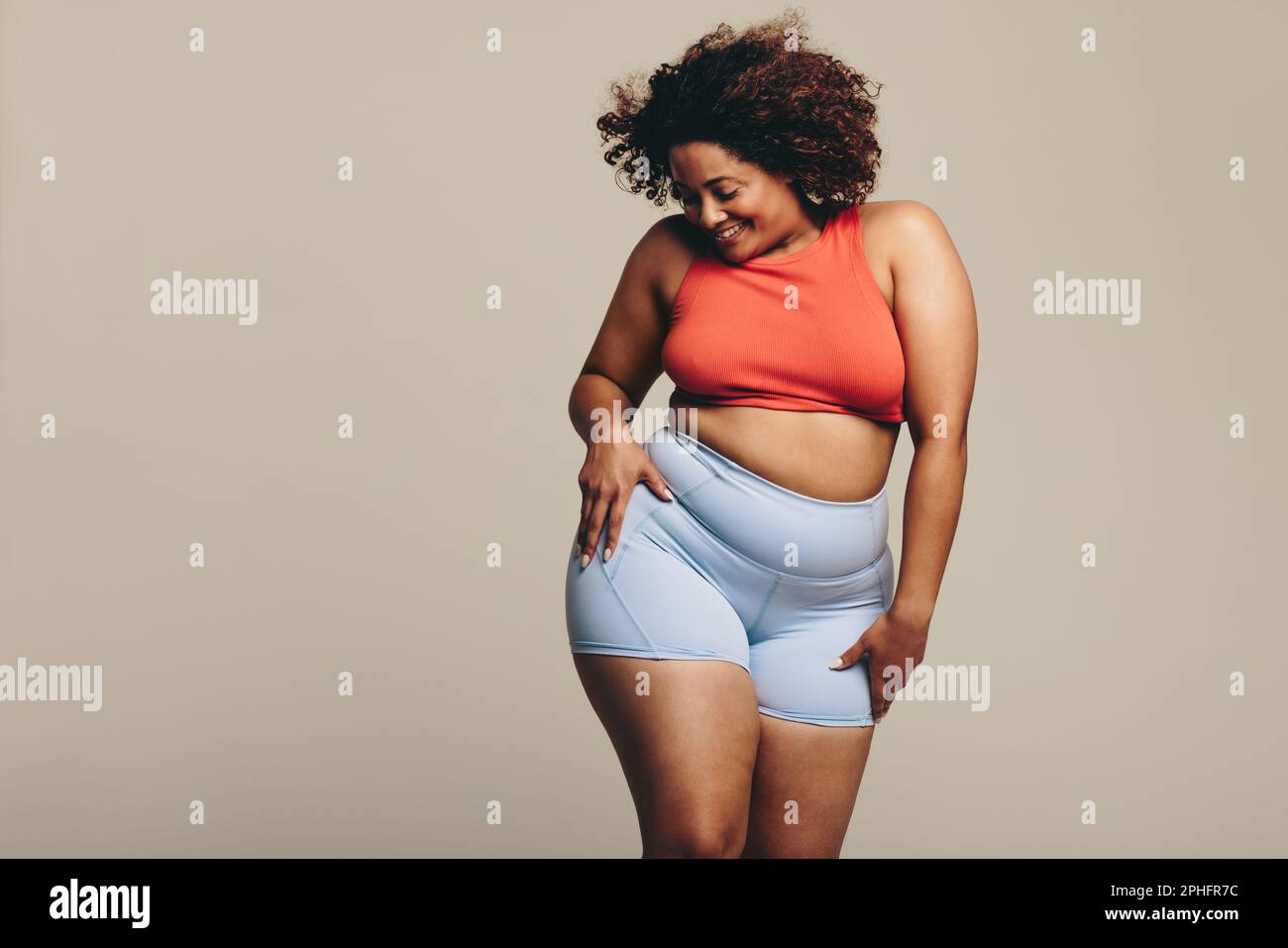 Donna in abbigliamento sportivo che mostra la sua forma fisica e la flessibilità attraverso la danza. Con un'espressione sicura, celebra il suo viaggio di fitness, fornisce Foto Stock