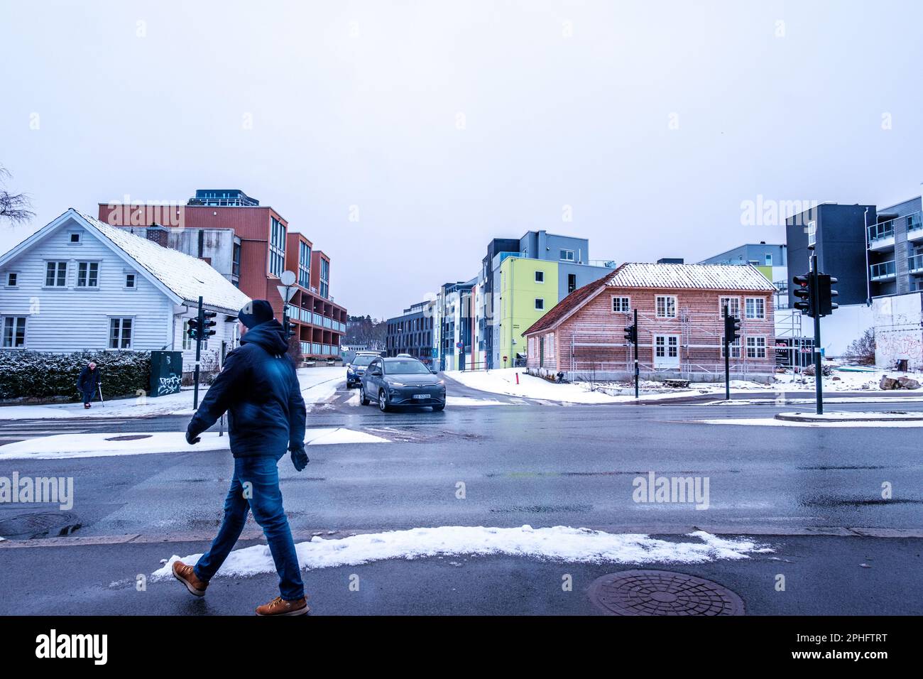 Sandnes, Norvegia, 11 2023 marzo, One Man Crossing Main Road o Highway Downtown Sandnes con auto in attesa al semaforo rosso Foto Stock