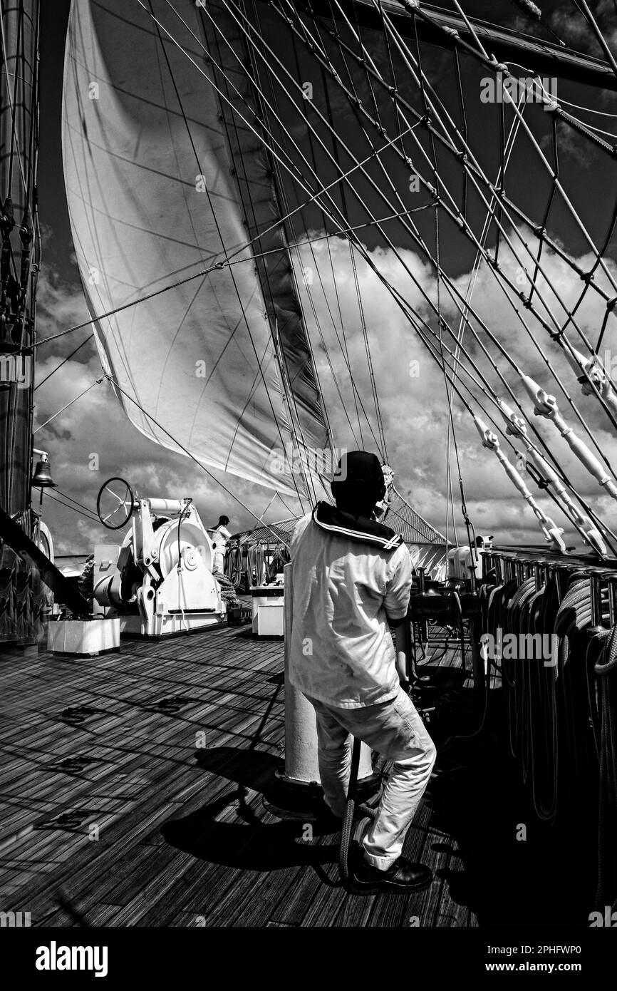 15Feb2023 Barbados Caribbean Royal Clipper Crew vestito in uniforme, che trasporta le vele sul ponte anteriore mentre è in corso durante una crociera in versione B&W. Foto Stock